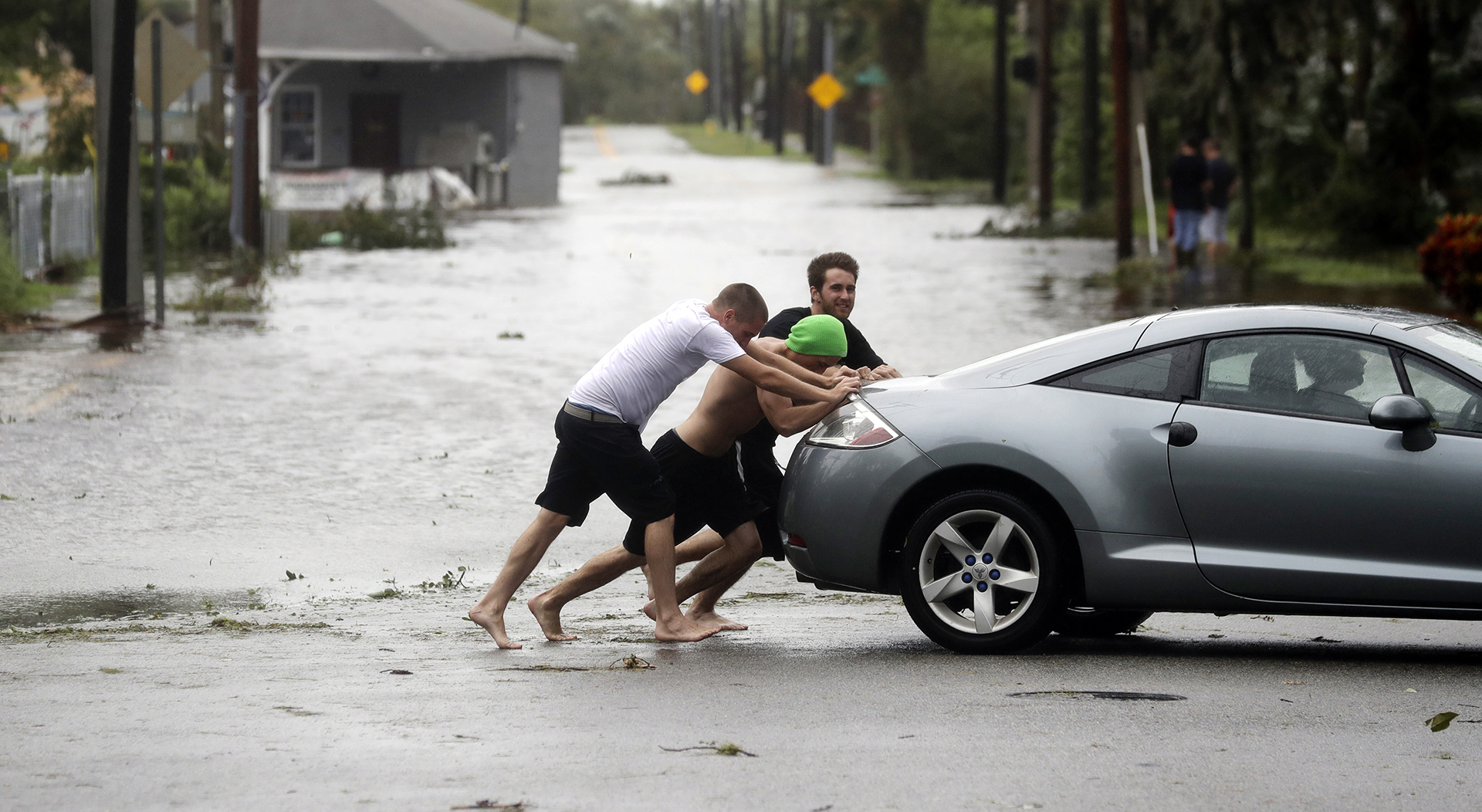Noah Simons empuja a su auto, que había sido arrastrado por las inundaciones en Daytona Beach (AP Photo/Eric Gay)