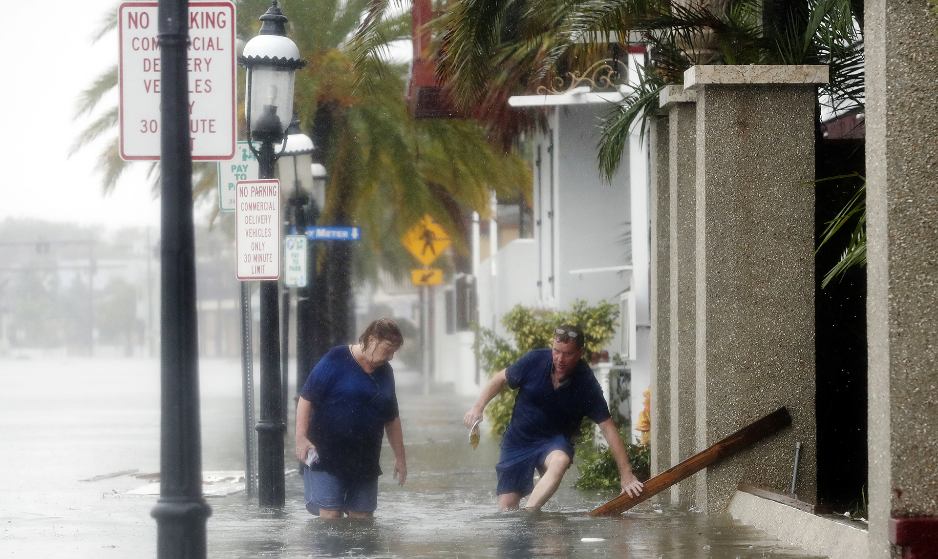 Un hombre y una mujer tratan de abrirse paso en una calle inundada en St. Augustine (AP Photo/John Bazemore)