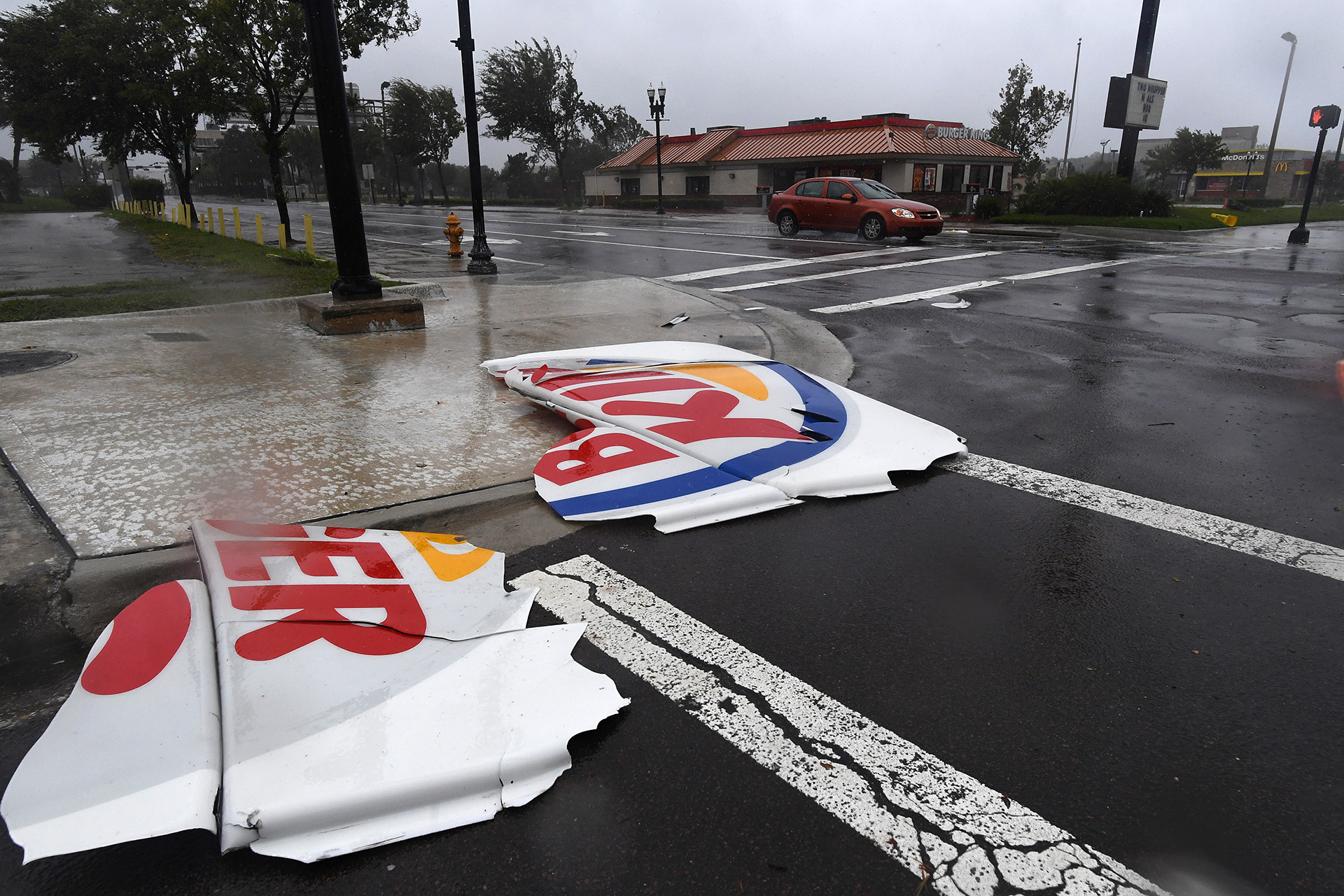 Un auto pasa a metros de un cartel de Burger King que quedó despedazado en Jacksonville (AFP PHOTO / JEWEL SAMAD)