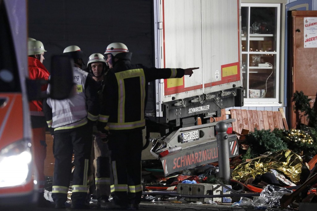 Bomberos junto a parte de los destrozos dejados por el camión que embistió el mercado navideño (Reuters)