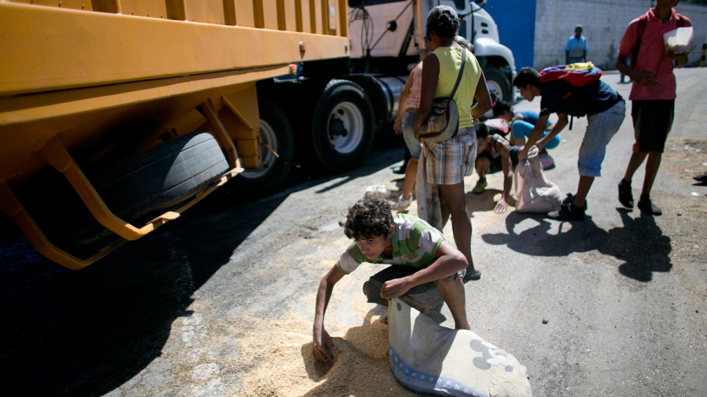 La gente, desesperada, recurre a levantar lo que cae de los camiones (AP)