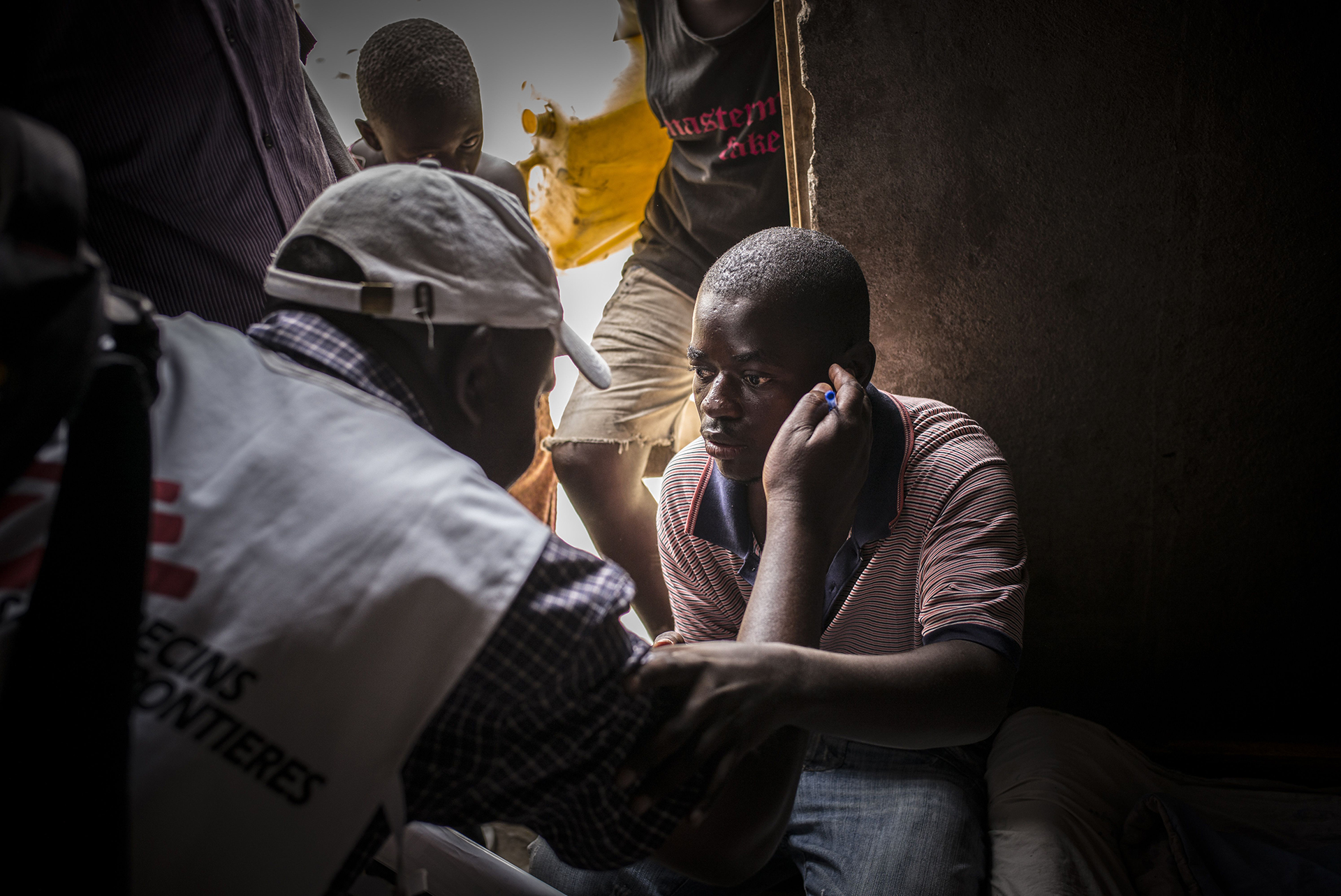 KATWE, UGANDA: Un trabajador de MSF hablando con un hombre con VIH positivo que perdió la vista y el oído cuando dejó de tomar sus medicamentos antirretrovirales a causa del estigma social. Los equipos de MSF pasan casa por casa a hacer pruebas de VIH en Katwe, Uganda (©Guillaume Binet/MYOP)