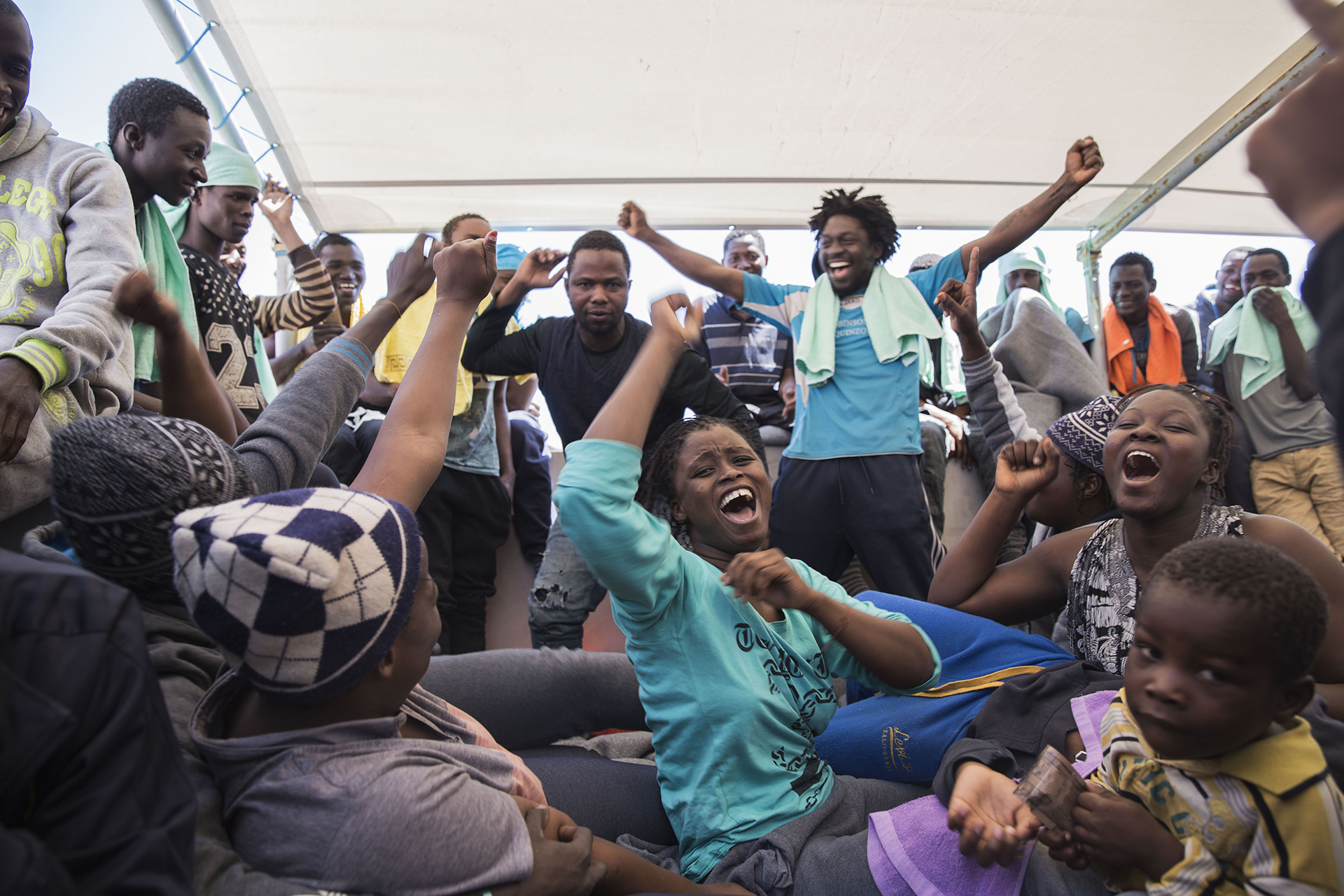 MAR MEDITERRÁNEO: A bordo del Dignity 1, un barco de búsqueda y rescate de MSF, un grupo de personas celebran haber sido rescatadas de un bote en peligro. Alrededor de 435 personas fueron salvadas, la mayoría eran de Guinea, Mali, Costa de Marfil y Senegal (© Anna Surinyach)