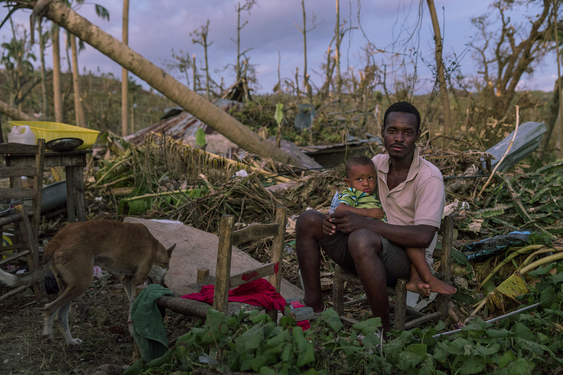 PORT SALUT, HAITÍ: Un hombre sentado junto a su hijo en lo que quedó de su hogar cerca de Port-Salut, en el sureste de Haití. El huracán Matthew arrasó en el Caribe el 4 de octubre, devastando grandes partes de la isla (©Andrew McConnell/Panos Pictures)