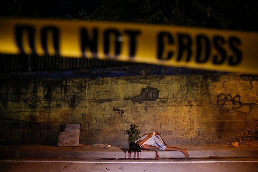 El cuerpo de otra víctima, muerta a tiros por pistoleros desconocidos, sangra detrás de una línea policial en Manila (Reuters)