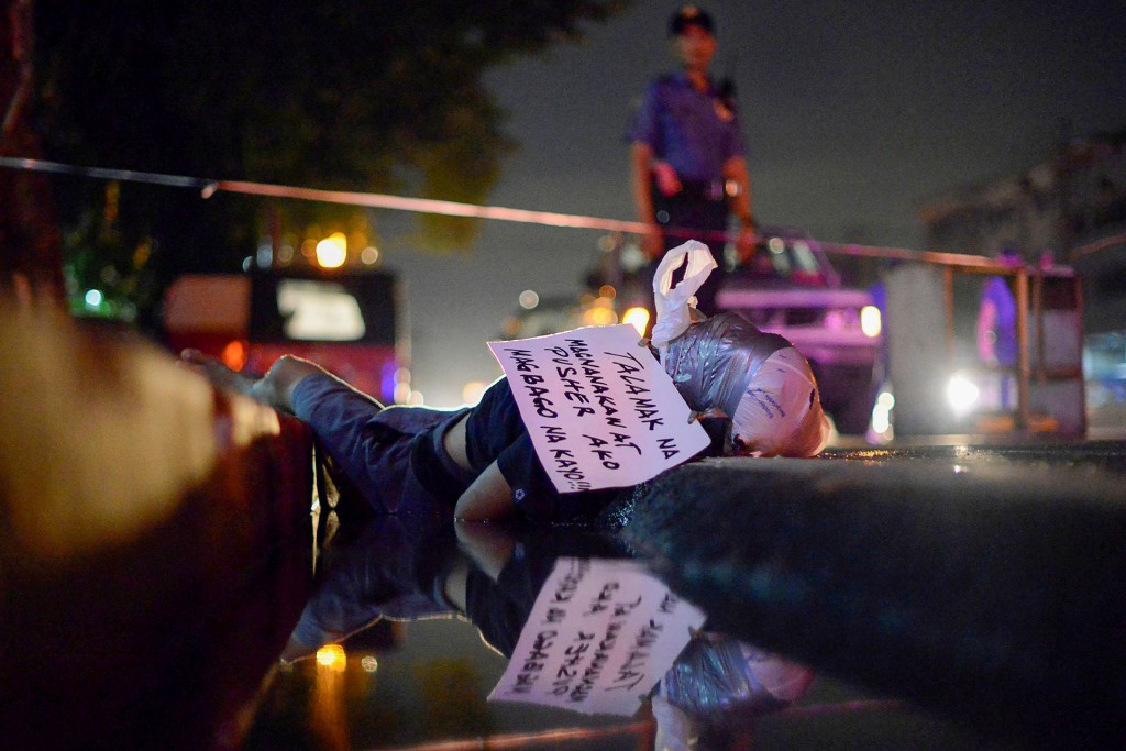 El cuerpo de un hombre, con la cabeza envuelta en cinta adhesiva, se encuentra en una cuneta de Manila. La nota manuscrita atada a su cabeza dice en filipino: “Soy un ladrón crónico. Es mejor cambiar!” (Reuters)