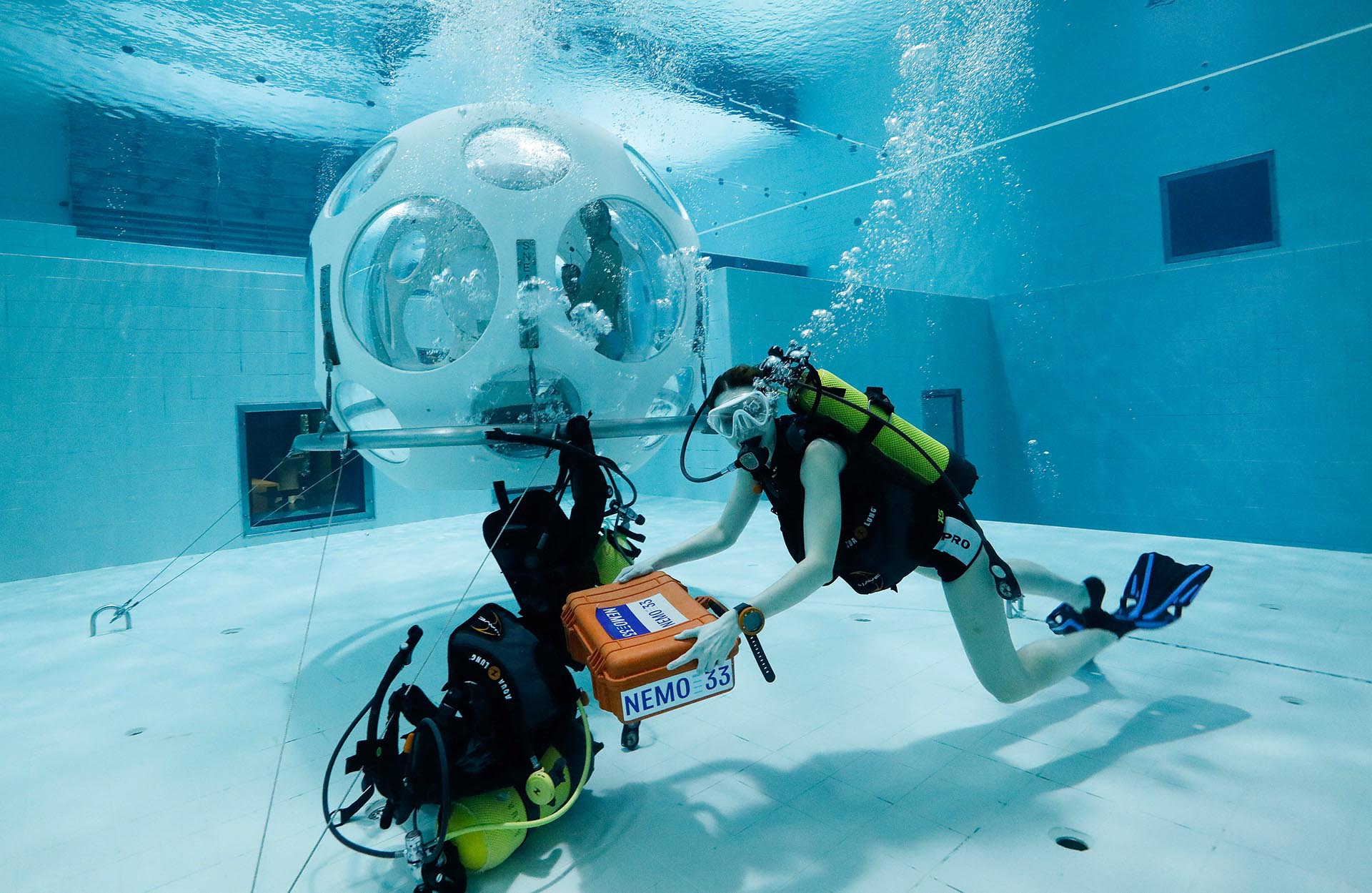 La mesera Valeryia Prusakova lleva uno de los pedidos en la caja hermética identificada con el nombre del centro de buceo, NEMO33 (REUTERS/Yves Herman)