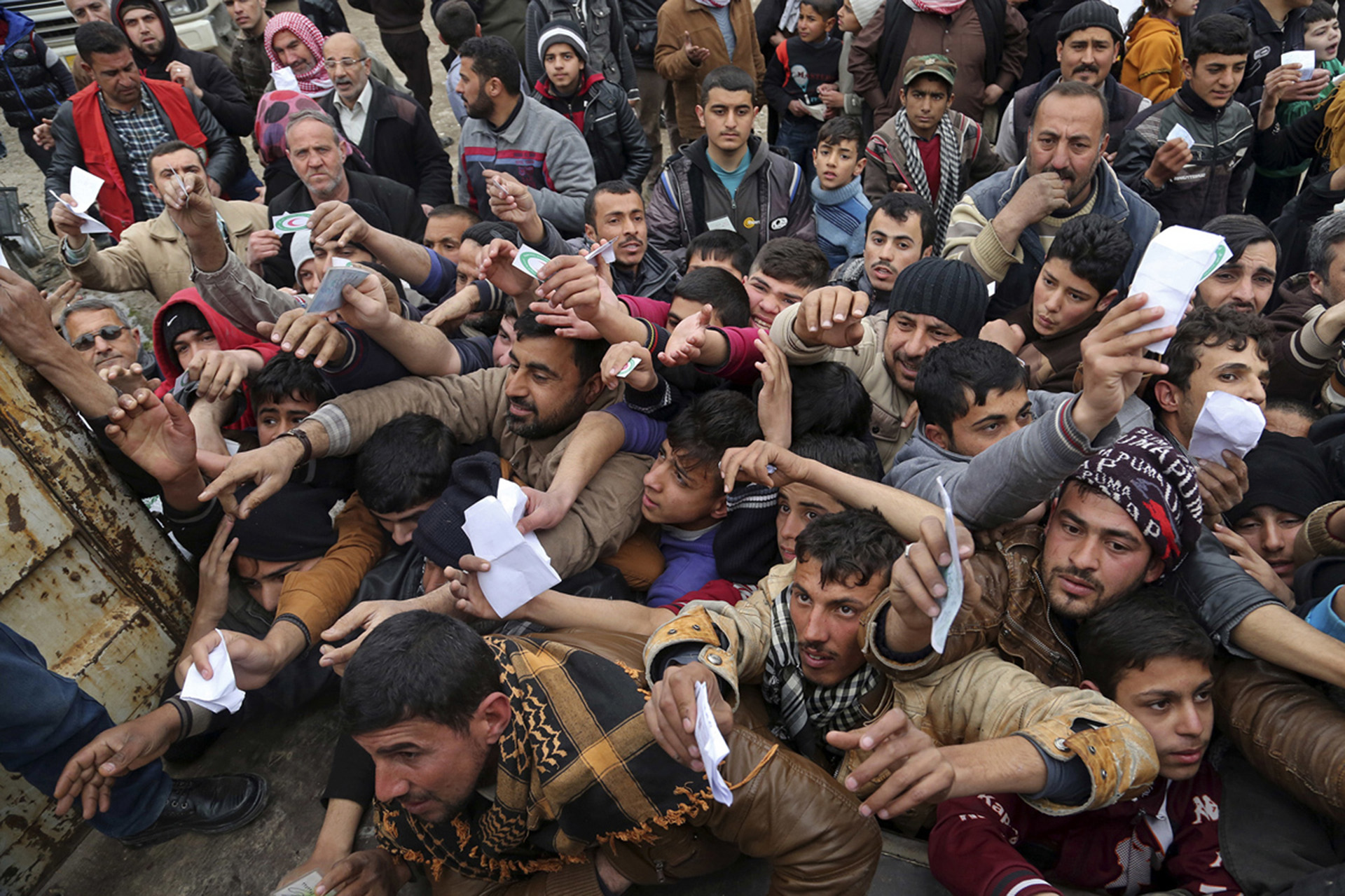 Habitantes de Mosul presentan sus tarjetas de racionamiento para recibir comida destribuida por la Media Luna Roja (AP)
