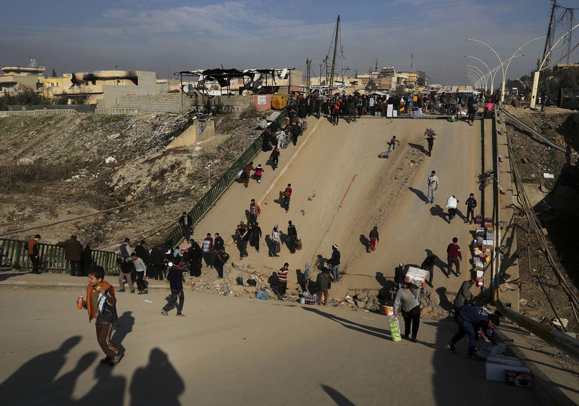 La gente cruza uno de los puentes que atraviesan el Tigris y que fueron destrozados por el ISIS (AP)