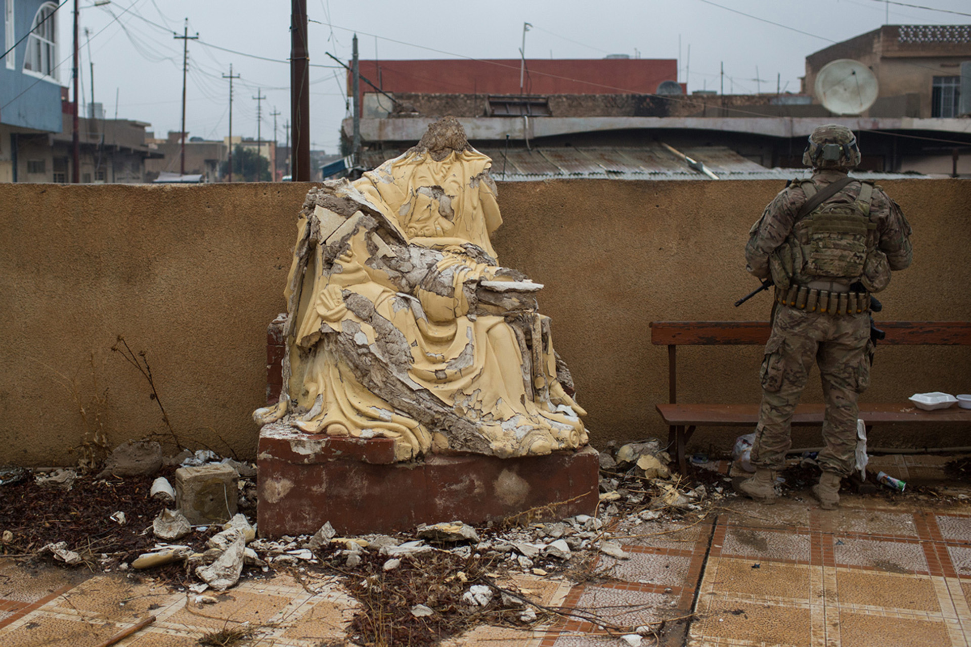 Un soldado estadounidense junto a una estatua cristiana destruida. Bartella y Qaraqosh son dos pueblos cristianos en las afueras de Mosul recientemente liberados (Getty)