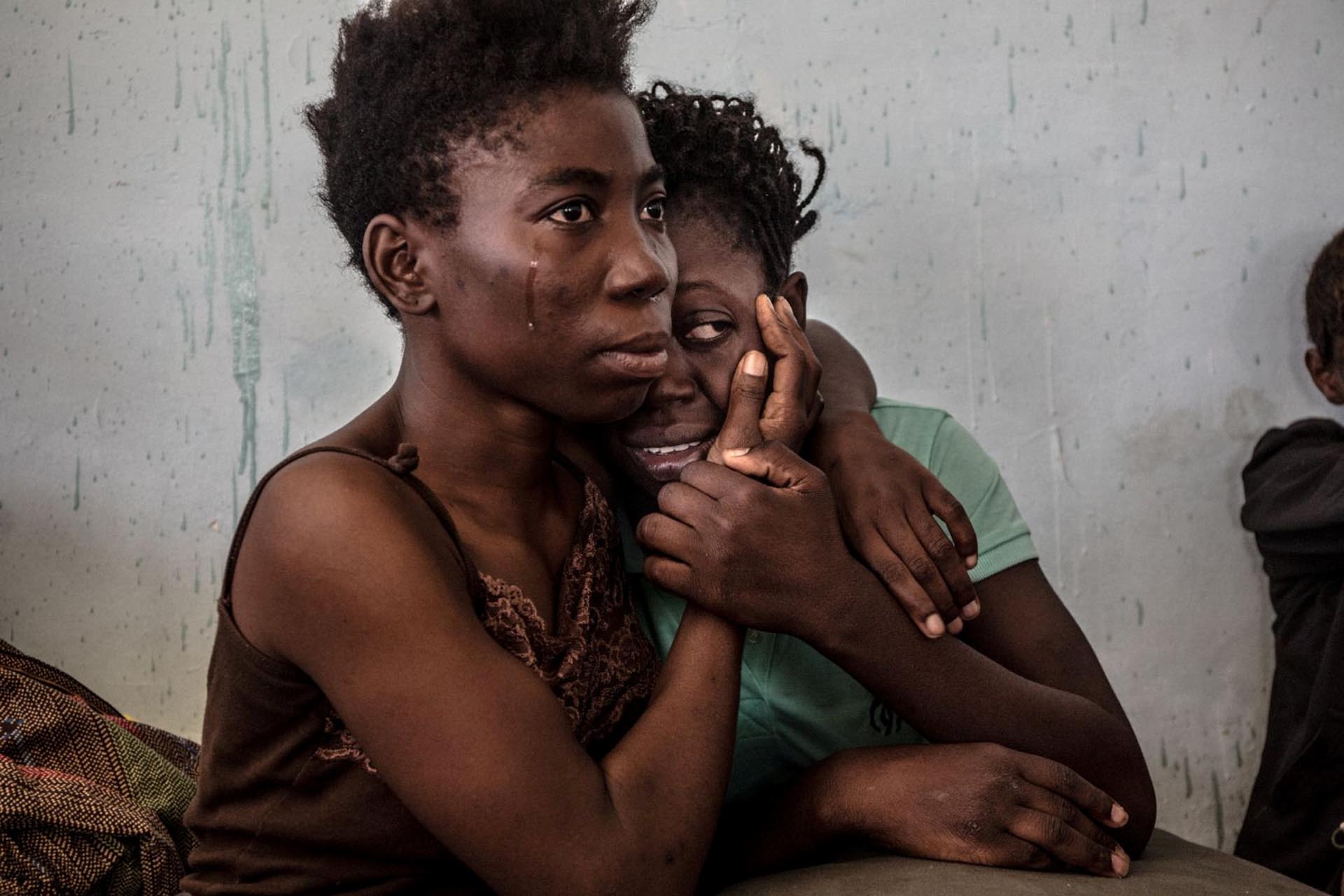 Asuntos Contemporáneos, tercer premio. Dos nigerianas refugiadas lloran en un centro en Suman, Libia. Daniel Ette, REUTERS