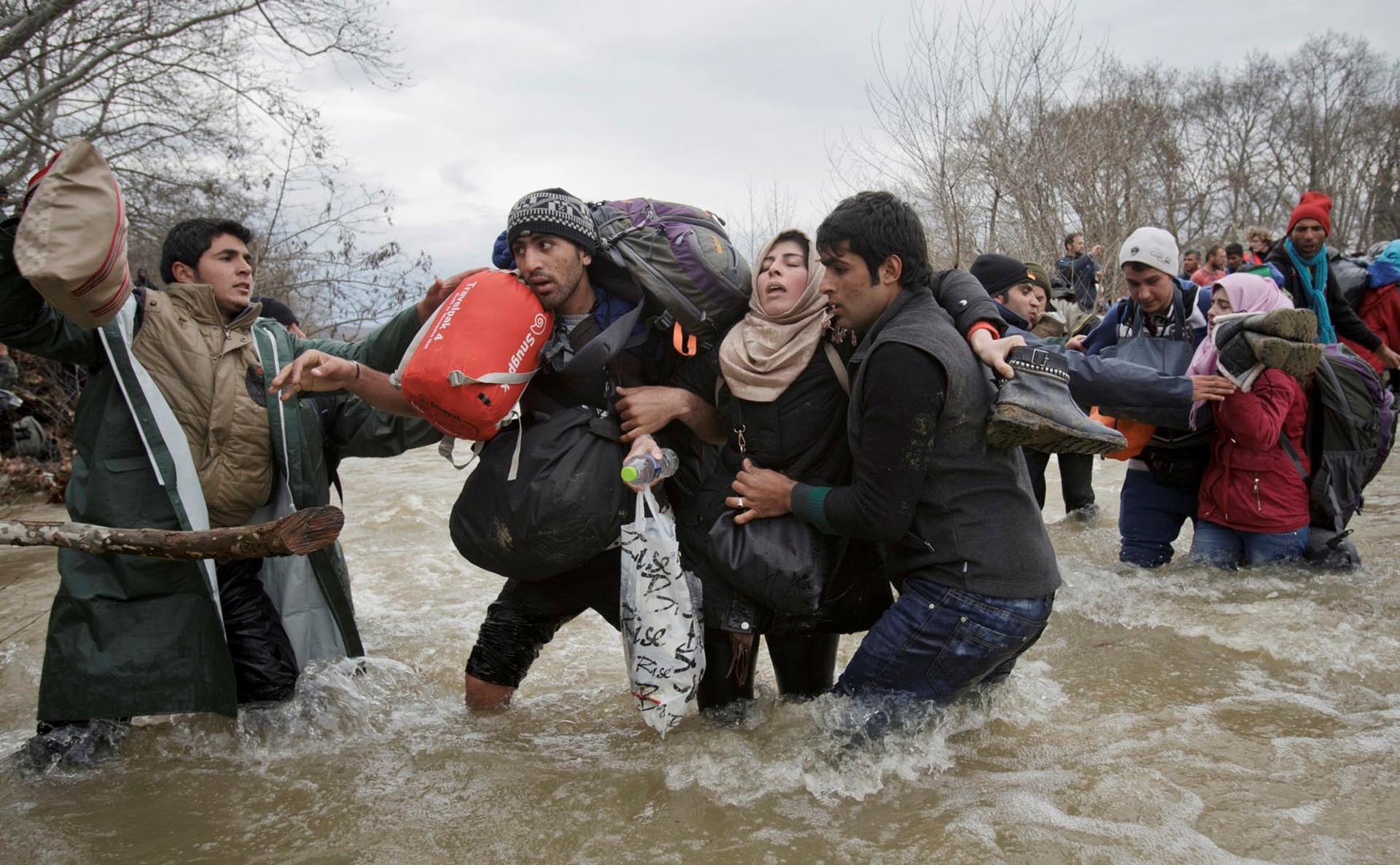 Asuntos Contemporáneos, segundo premio. El cruce de los inmigrantes. Una mujer recibe el apoyo de dos hombres mientras cruzan un río en el intento por alcanzar Macedonia por una ruta que esquiva la seguridad fronteriza. Vadim Ghirda, The Associated Press