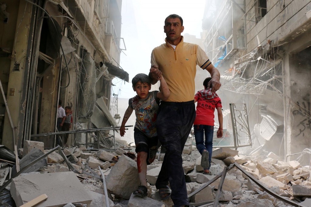Un hombre sirio y un niño evacúan el área luego de bombardeos en el barrio de Hayy Aqyul, en Alepo. Ameer Alhalbi, Agence France-Presse