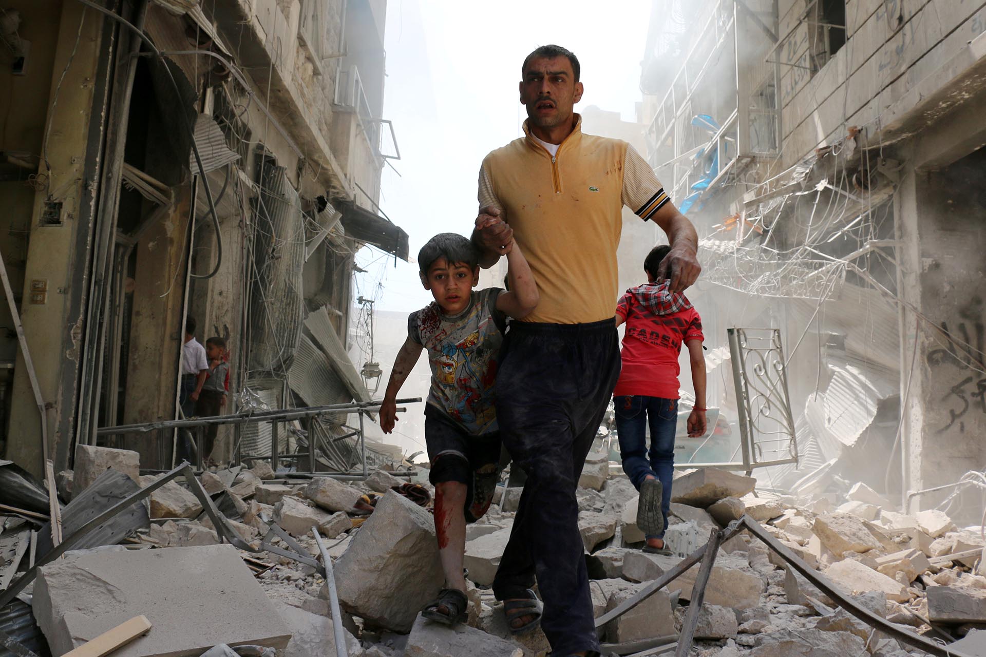 Spot News, segundo premio. Un hombre sirio y un niño evacúan el área luego de bombardeos en el barrio de Hayy Aqyul, en Alepo. Ameer Alhalbi, Agence France-Presse