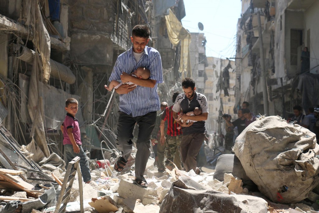 Hombres sirios cargan bebés mientras se abren paso entre los escombros de edificios destruidos tras un bombardeo en Alepo, el 11 de septiembre de 2016. Ameer Alhalbi, Agence France-Presse