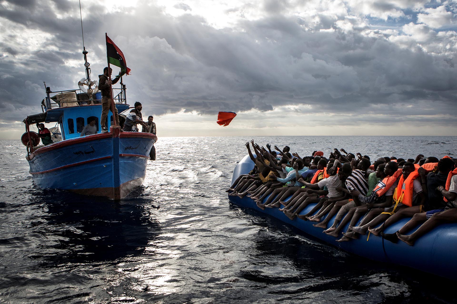 Spot News, tercer premio. Pescadores libios arrojan chalecos salvavidas a un precario bote lleno de migrantes. Mathieu Willcocks/MOAS.eu