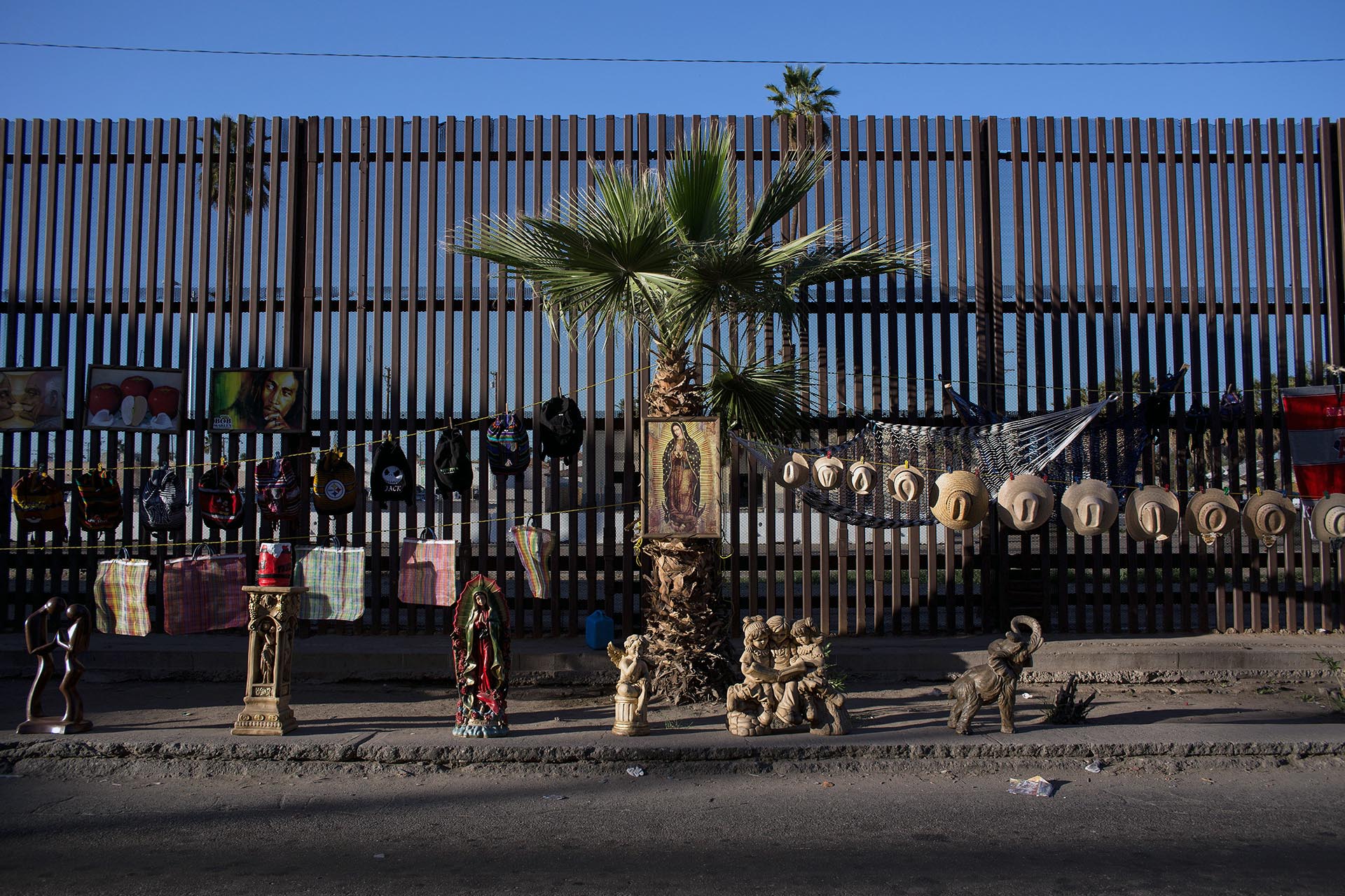 Vendedores ambulantes despliegan sus productos sobre la valla de la frontera mexicana, en Mexicali