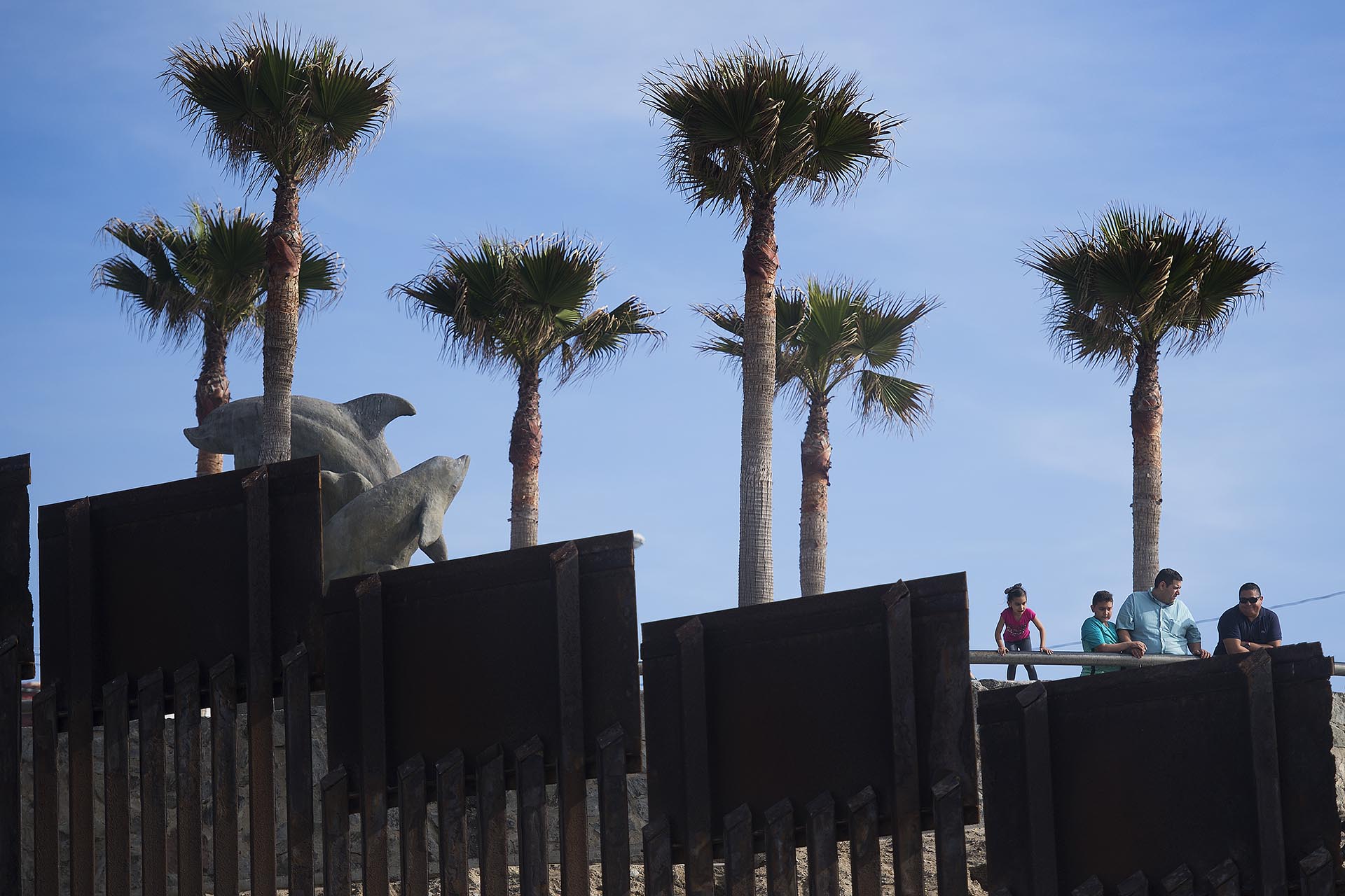 Habitantes de Tijuana, México, se asoman sobre la frontera que separa las playas en el parque estatal de San Diego, California