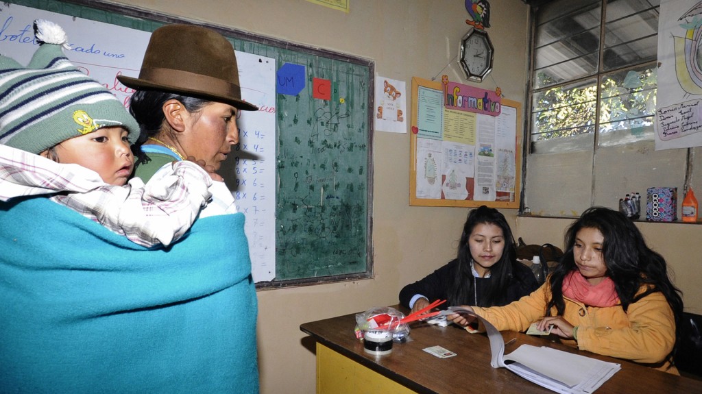 Una mujer espera para votar junto a su hijo en el colegio “José Acosta Vallejo” en Cangahua (AFP)