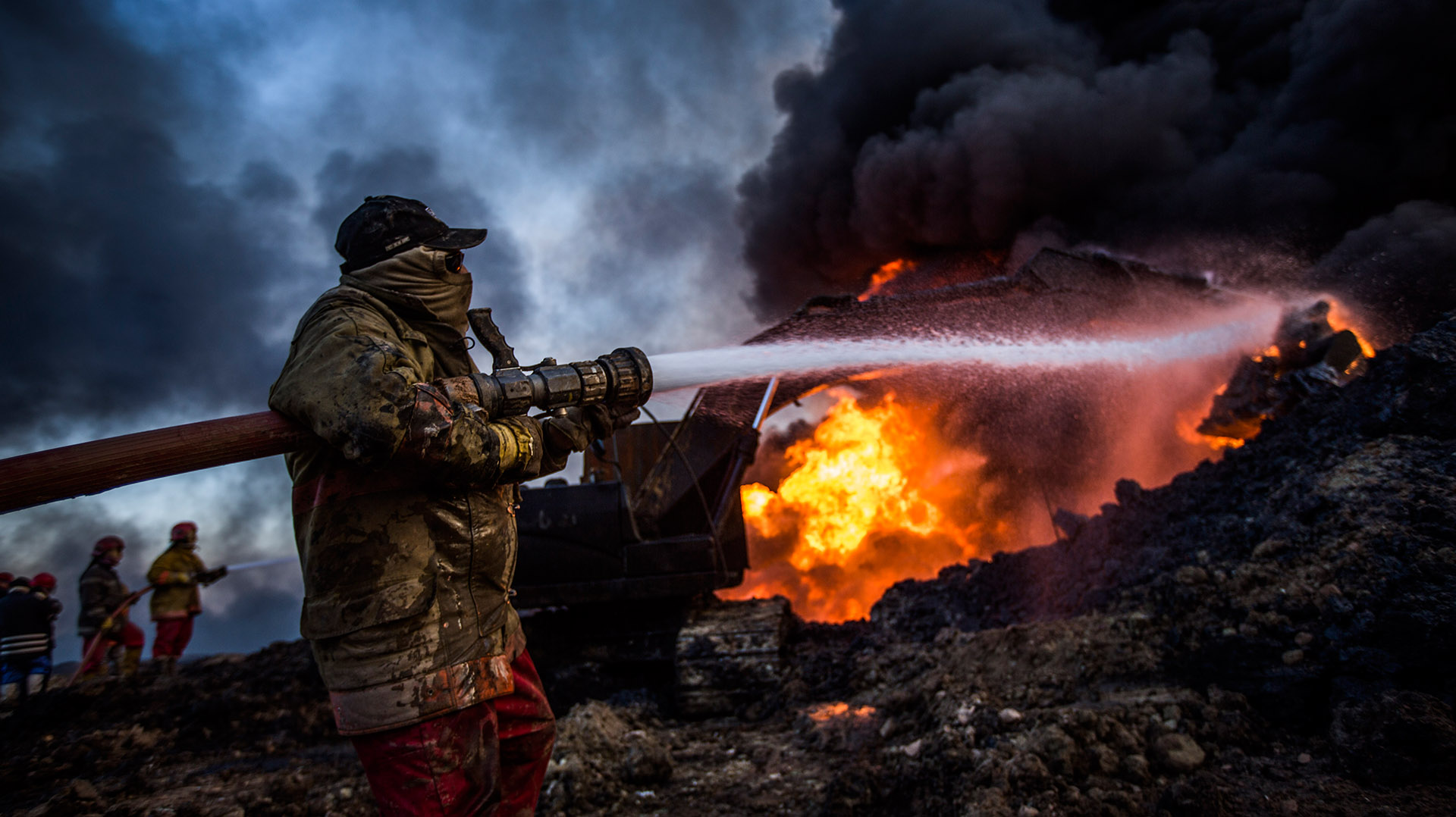 Divididos en dos equipos, los bomberos trabajan para sofocar la gran columna de fuego. Mientras la primera unidad lanza agua al interior del pozo, la segunda se encarga de refrescar la maquinaria para que no sea también pasto de las llamas. (Pablo Cobos)