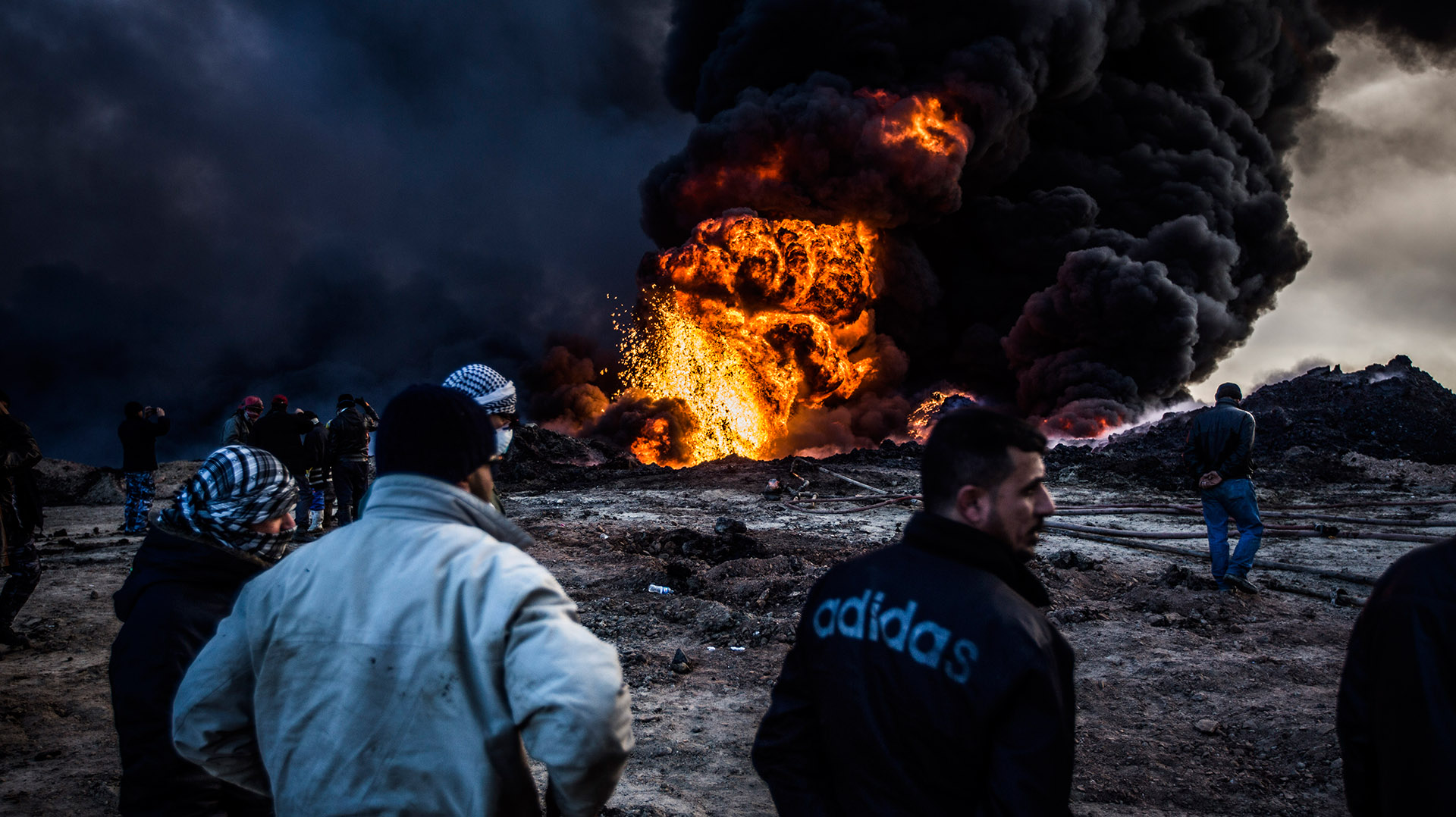 Un grupo de bomberos fuera de servicio observan el trabajo de sus compañeros desde la distancia. El calor hace imposible acercarse sin el equipo de protección. (Pablo Cobos)