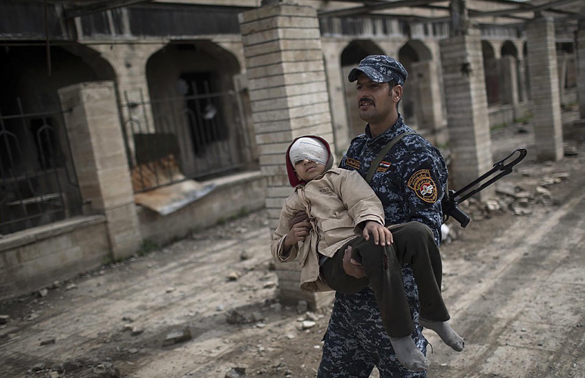 Un militar iraquí carga a un niño herido (AP)