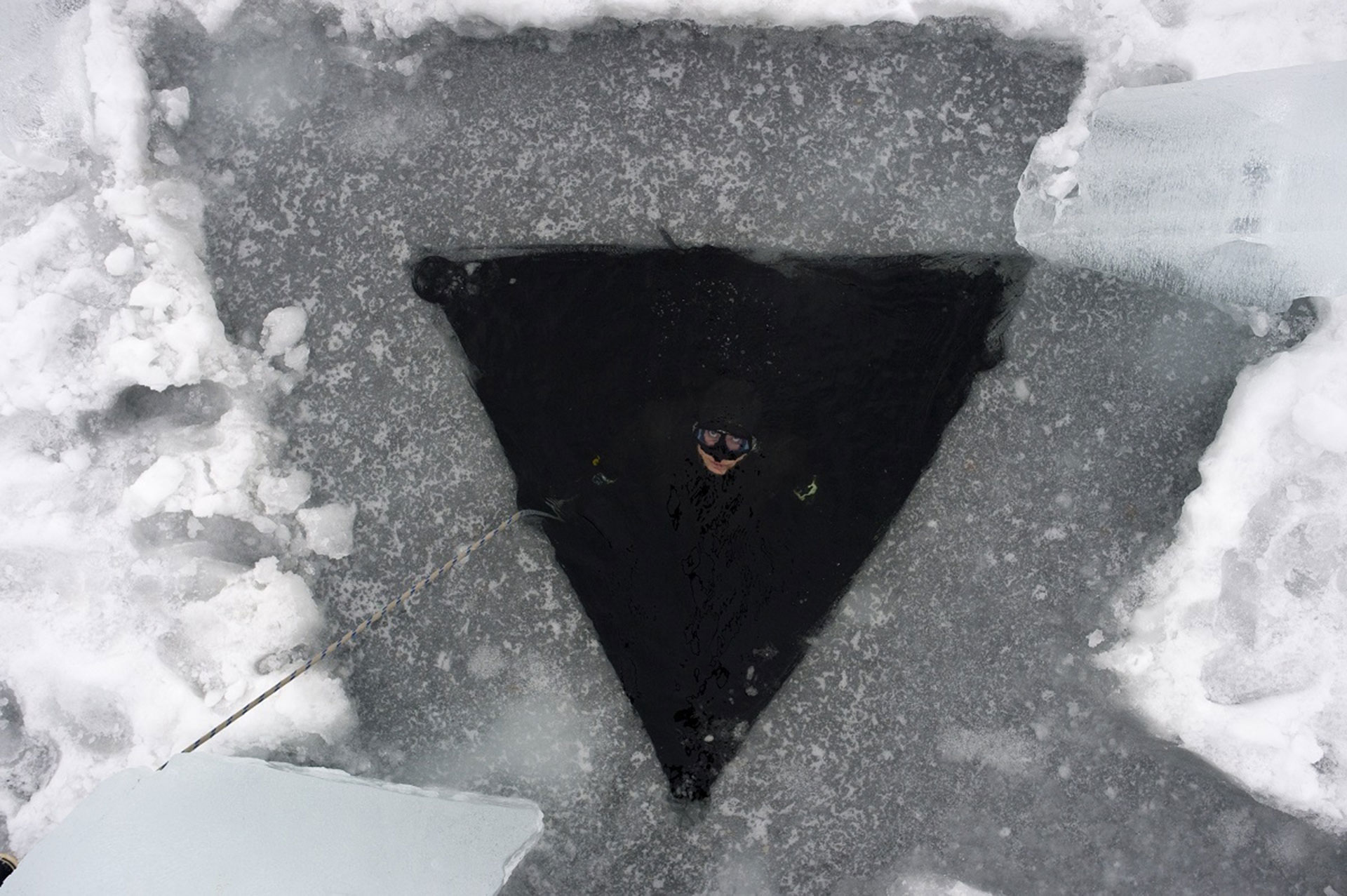 El agujero triangular que deben taladrar para bucear bajo hielo (AFP)