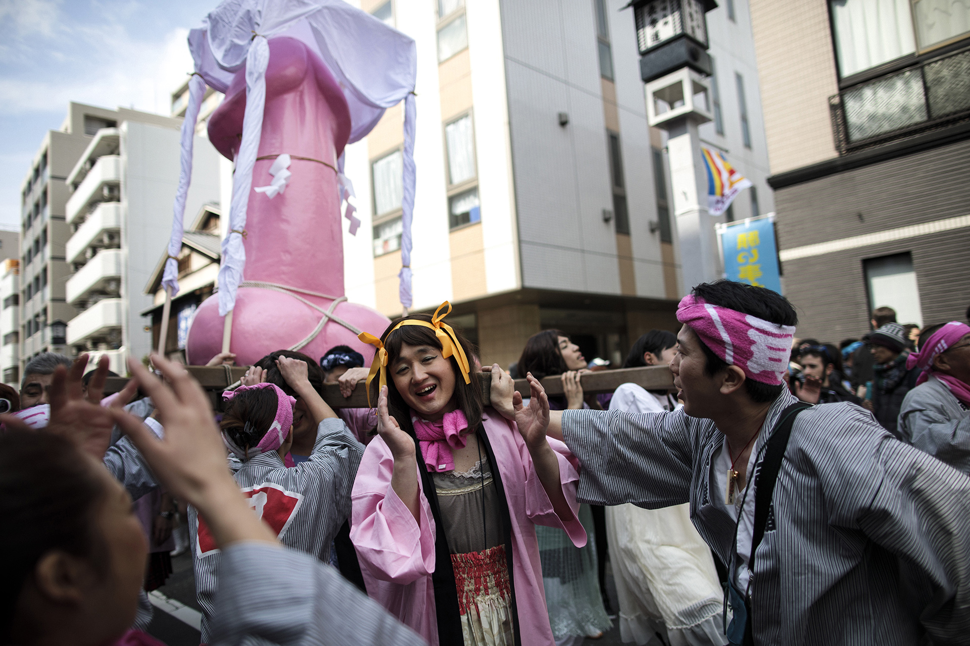 Una mujer posa al lado del monumento fálico que cargan durante el Festival del Pene de Acero en Kawasaki (AFP)