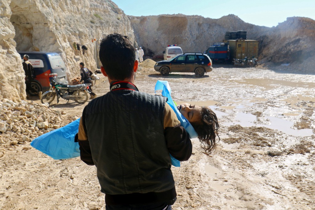 Un hombre carga el cádaver de una niña tras el ataque químico (Reuters)