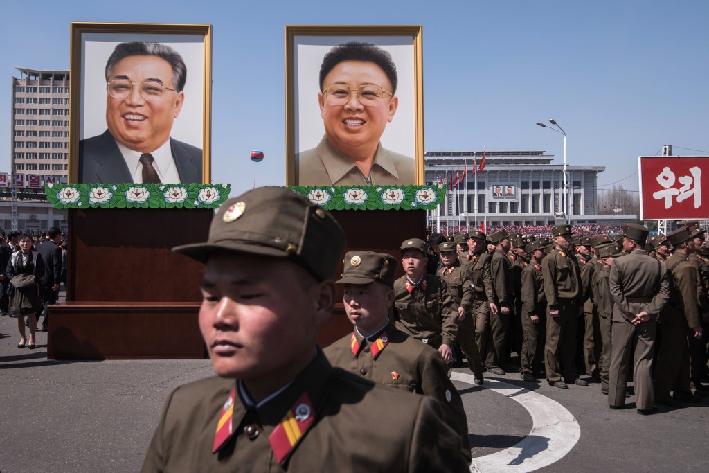 Soldado del ejÃ©rcito norcoreano junto y los restratods de los fallecidos lÃ­deresÂ Kim Il-Sung (izquierda) y Kim Jong-Il (derecha) (AFP PHOTO / Ed JONES)