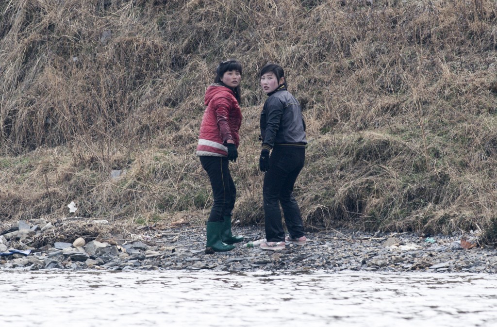 Dos mujeres norcoreanas observan a los turistas desde la orilla del río. Los cruceros por el Yalu son una verdadera industria en el puerto de Dandong, donde decenas de barcos llevan a los turistas por solo 70 yuanes (10 euros)