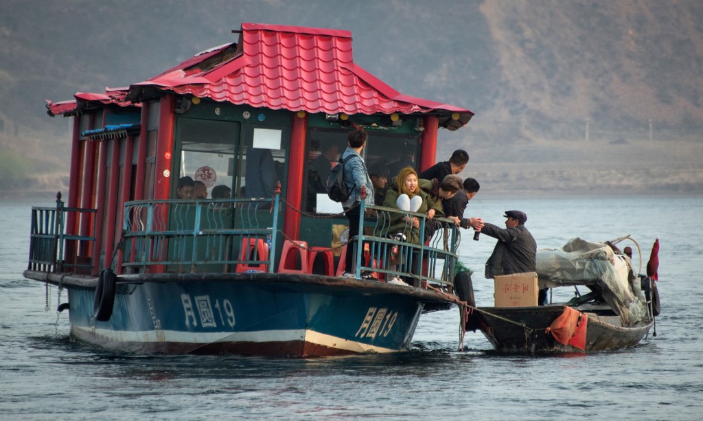 Un hombre vende productos norcoreanos a los turistas chinos que llegan en pequeños cruceros turísticos, en el río Yalu. Los barcos se acercan hasta tan sólo unos metros de la costa coreana, lo que permite a los turistas ver el país sancionado internacionalmente por su programa nuclear
