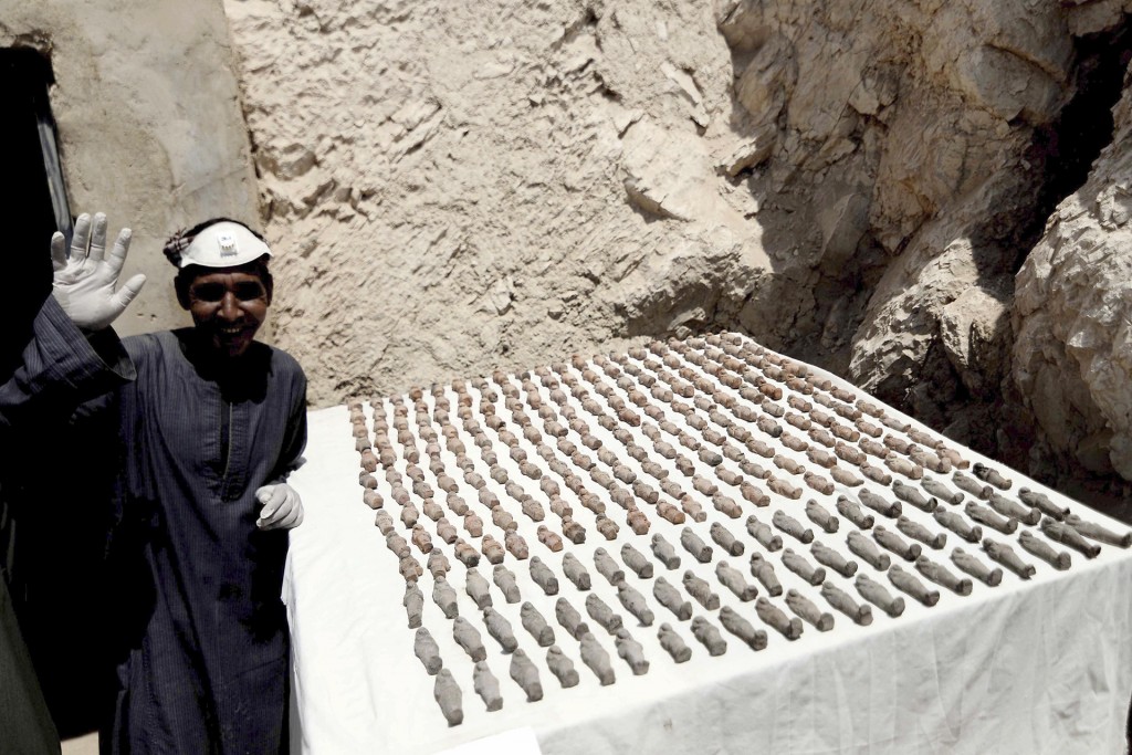 Un hombre saluda junto a estatuillas “ushabti” descubiertas. Los descubrimientos realizados en la cámara de la parte occidental serán revelados más adelante, ya que las excavaciones aún no han sido concluidas (EFE)