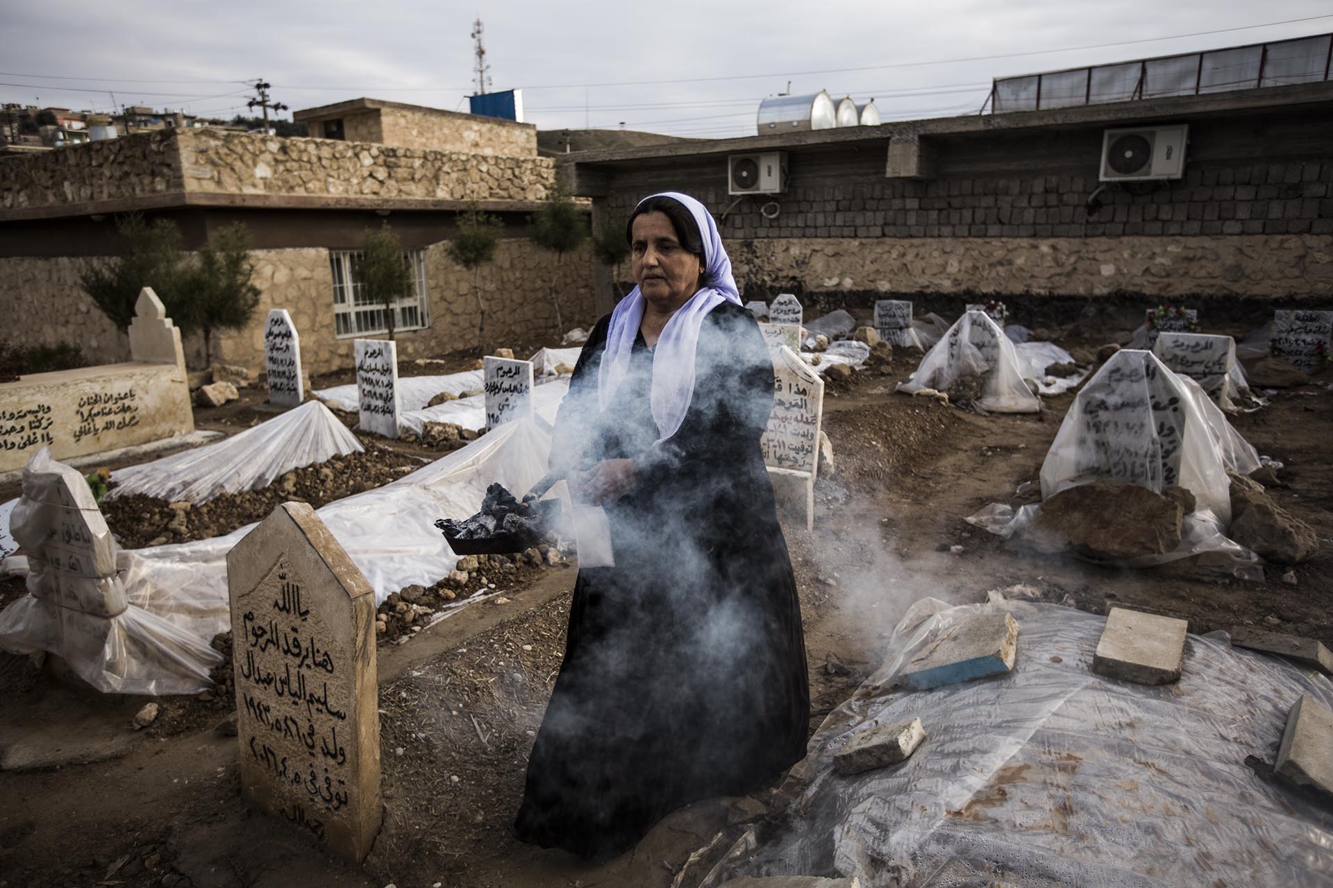 Una mujer purifica las tumbas de los yazidíes enterrados en el cementerio de Lalish durante la celebración del día de los muertos (Pablo Cobos)