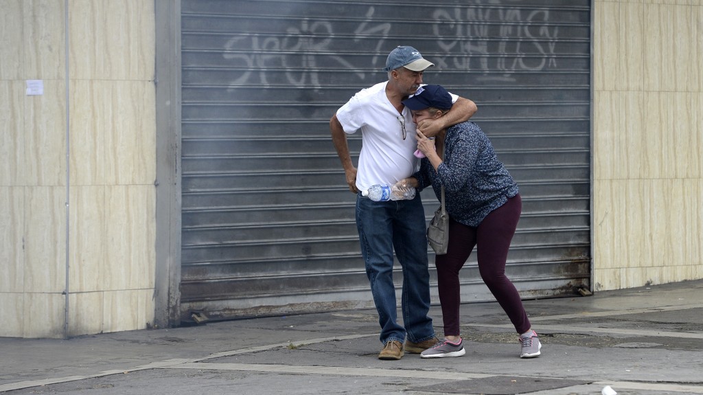 Una pareja intenta protegerse entre los gases lanzados por las fuerzas represivas