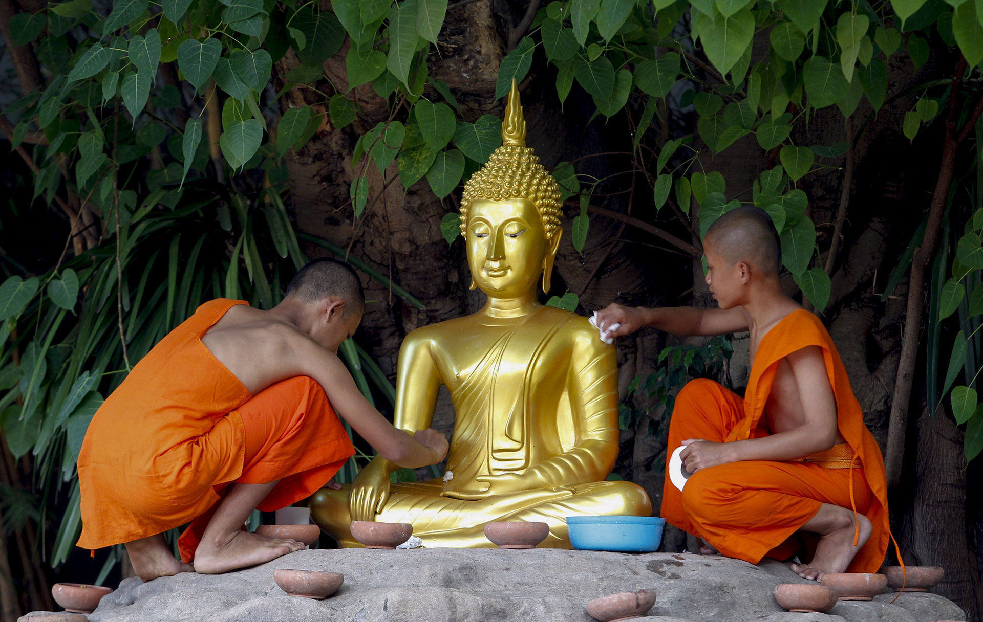 Dos monjes budistas limpian una escultura de Buda durante una ceremonia religiosa para celebrar el Día de Buda en la provincia de Chiang Mai (Tailandia) el 10 de mayo de 2017. (EFE)