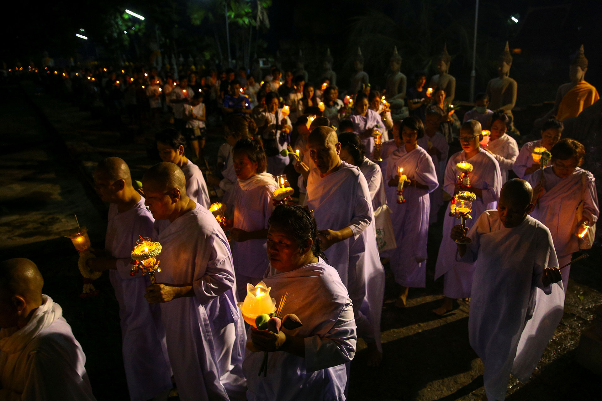 Monjas y monjes budistas cargan velas mientras rezan en el templo Chai Mongkhon en Ayutthaya, Tailandia el 10 de mayo de 2017. (Reuters)