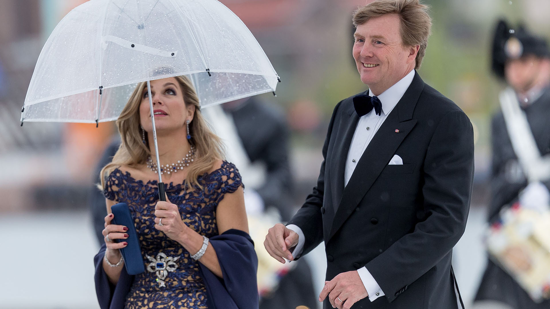 Al igual que el resto de los invitados, la reina de Holanda se refugió de la llovizna bajo un paraguas transparente