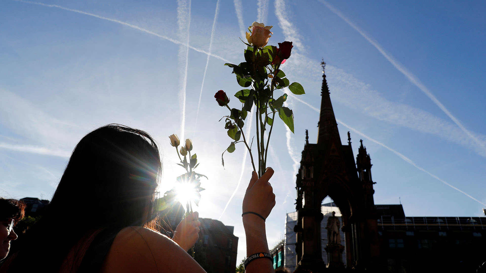 Una mujer sostiene un ramo de flores en medio de la vigilia (REUTERS)