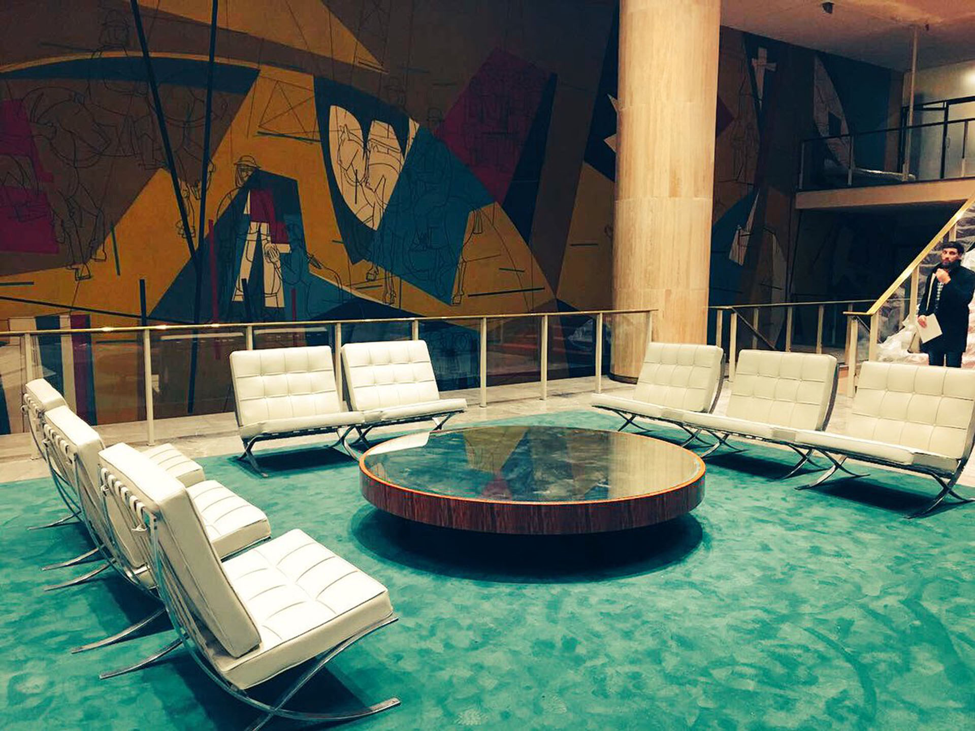 De fondo, el mural del maestro Seoane y en el centro una mesa espejo rodeada de ocho sillones “Barcelona”