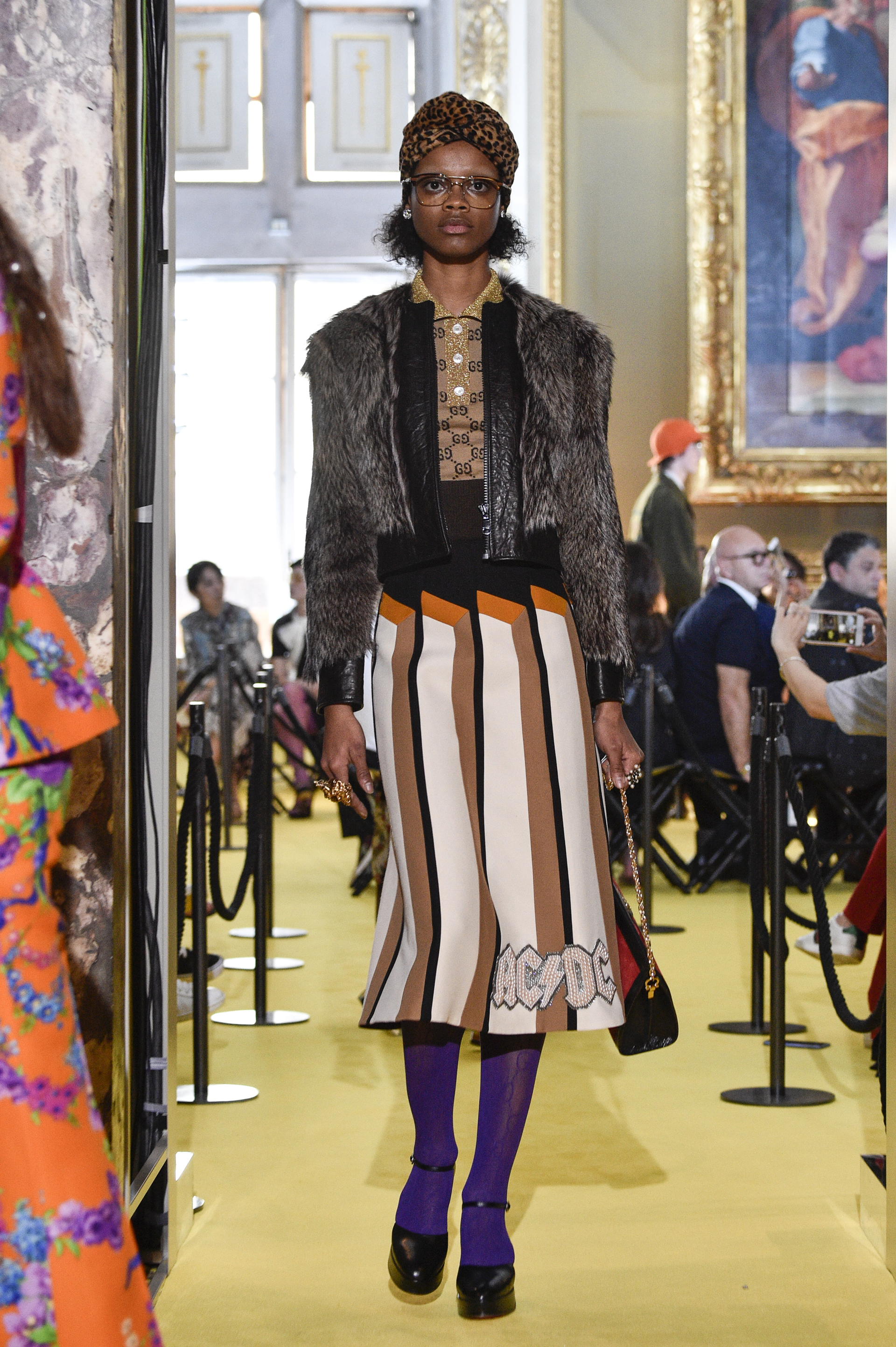 Con una camisa con pequeños logos de gucci, un saco de piel, pollera larga con el logo de acdc, una cartera clasica de la marca y medias violetas, este look deslumbró en la pasarela. ( Pietro D’Aprano/Getty Images)