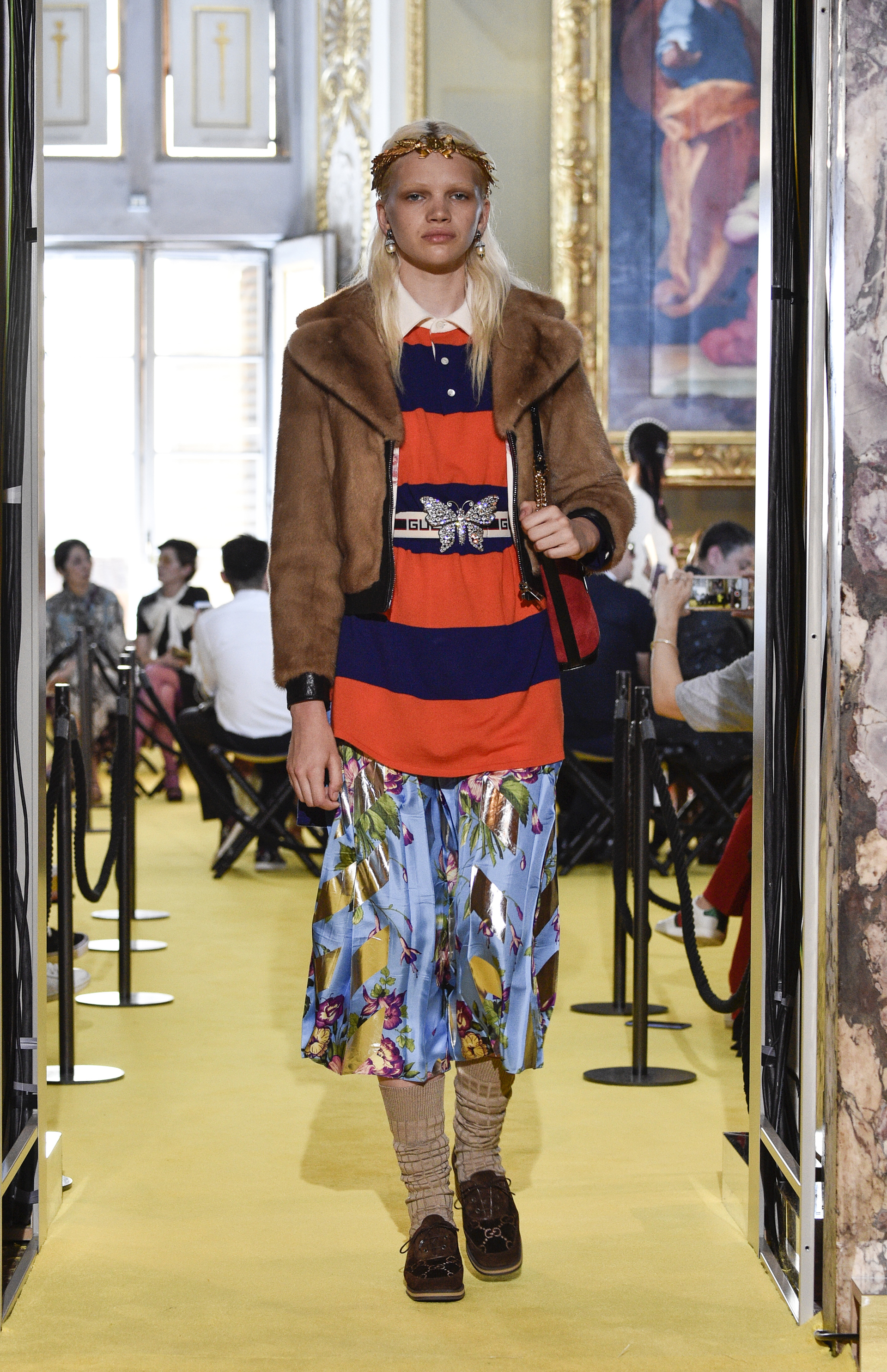 Uno de los looks más polemicos por su mezcla de estampados y texturas, medias altas ,una blusa con la inscripcion de la marca, falda estampada en flores y mix de dorado y el tapado de piel (Pietro D’Aprano/Getty Images)