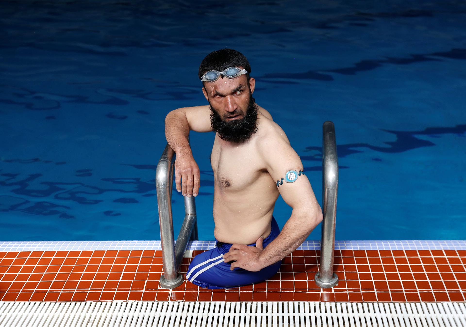 Khan Agha, de 28 años, se sienta al borde de una piscina durante su práctica en Kabul, Afganistán