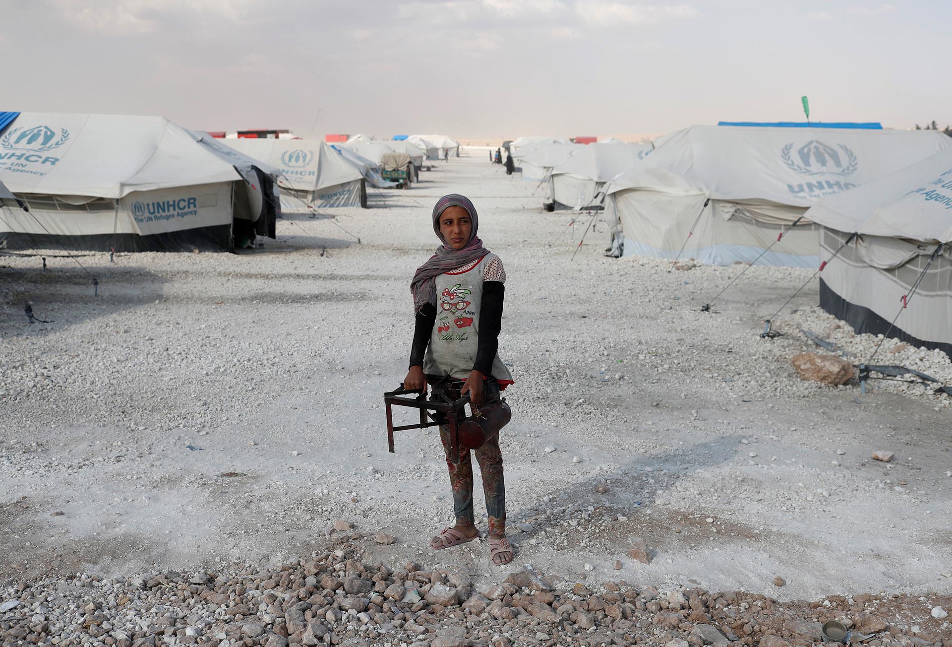 Una adolescente sostiene una cocina en un campamento para personas desplazadas de sus hogares en Ain Issa, Siria, por la violencia del Estado Islámico