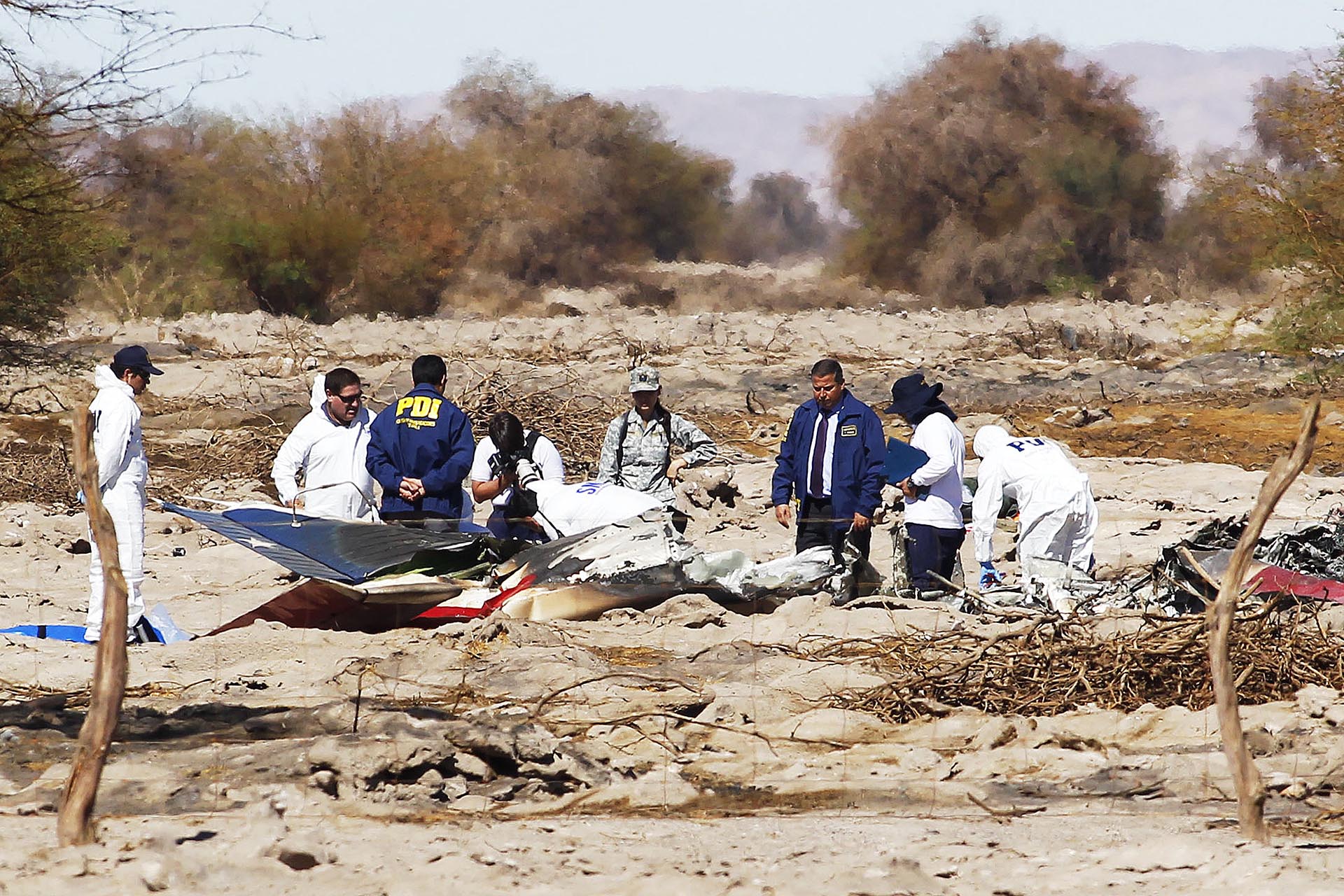 Funcionarios de la Policía de Investigaciones (PDI) trabajan en el área donde se accidentó una aeronave de la Fuerza Aérea de Chile (FACH) en Pozo Almonte