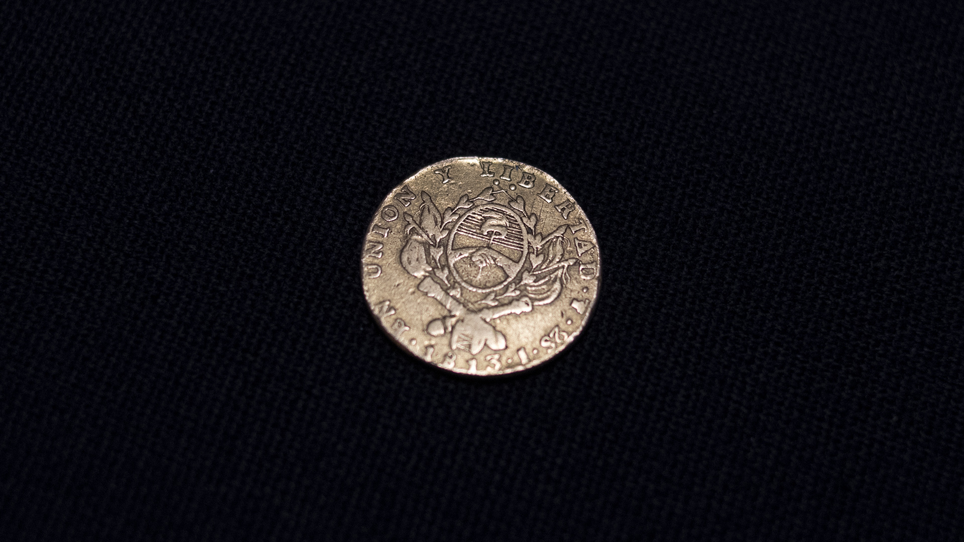 La moneda de dos escudos es la pieza más valiosa de toda la colección donada por Héctor Carlos Janson al Museo. Hay solo dos ejemplares. Acuñada en 1813 en la Casa de Moneda de Potosí por General Manuel Belgrano cumpliendo órdenes de la Asamblea del año XIII. Anverso el sello de la Asamblea General Constituyente y el reverso el Sol Patrio en la otra.(Adrián Escandar)
