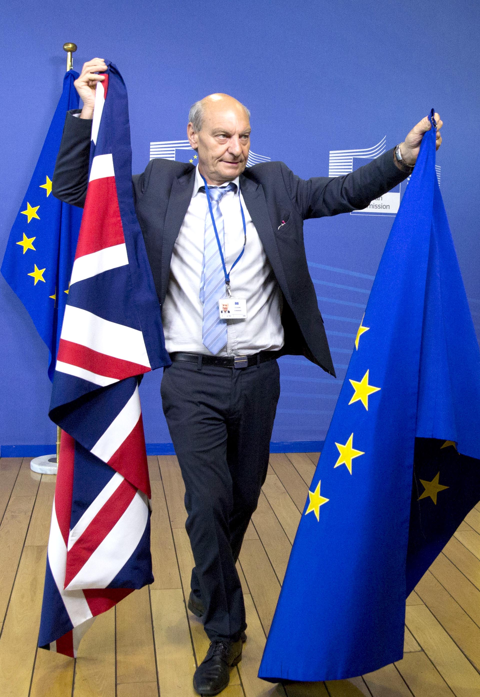 Un miembro del protocolo cambia las banderas de Gran Bretaña y de la Unión Europea antes del inicio de la discusión por el Brexit en Bruselas, Bélgica
