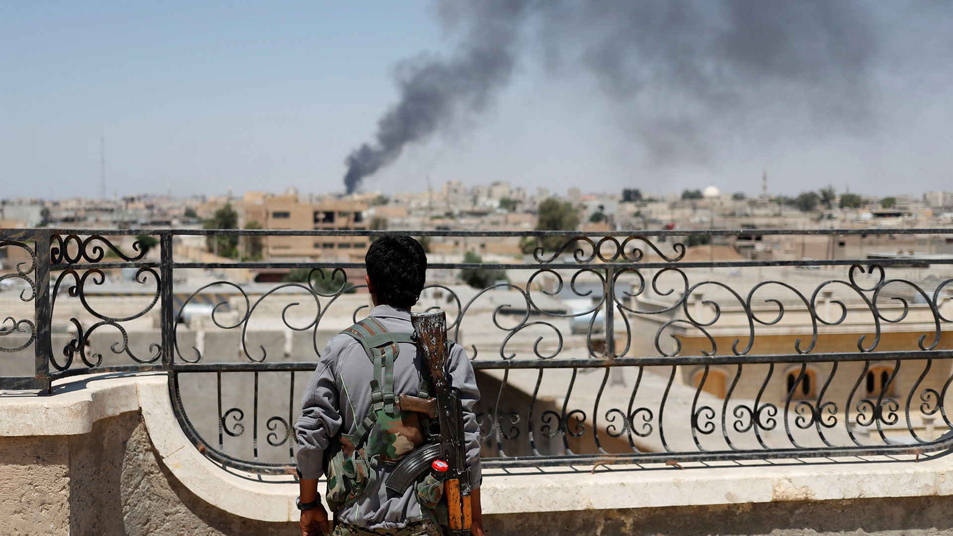 Un combatiente kurdo observa a la ciudad de Raqqa, en Siria, poco antes de la ofensiva final sobre la que fuera capital del “califato” (Reuters)