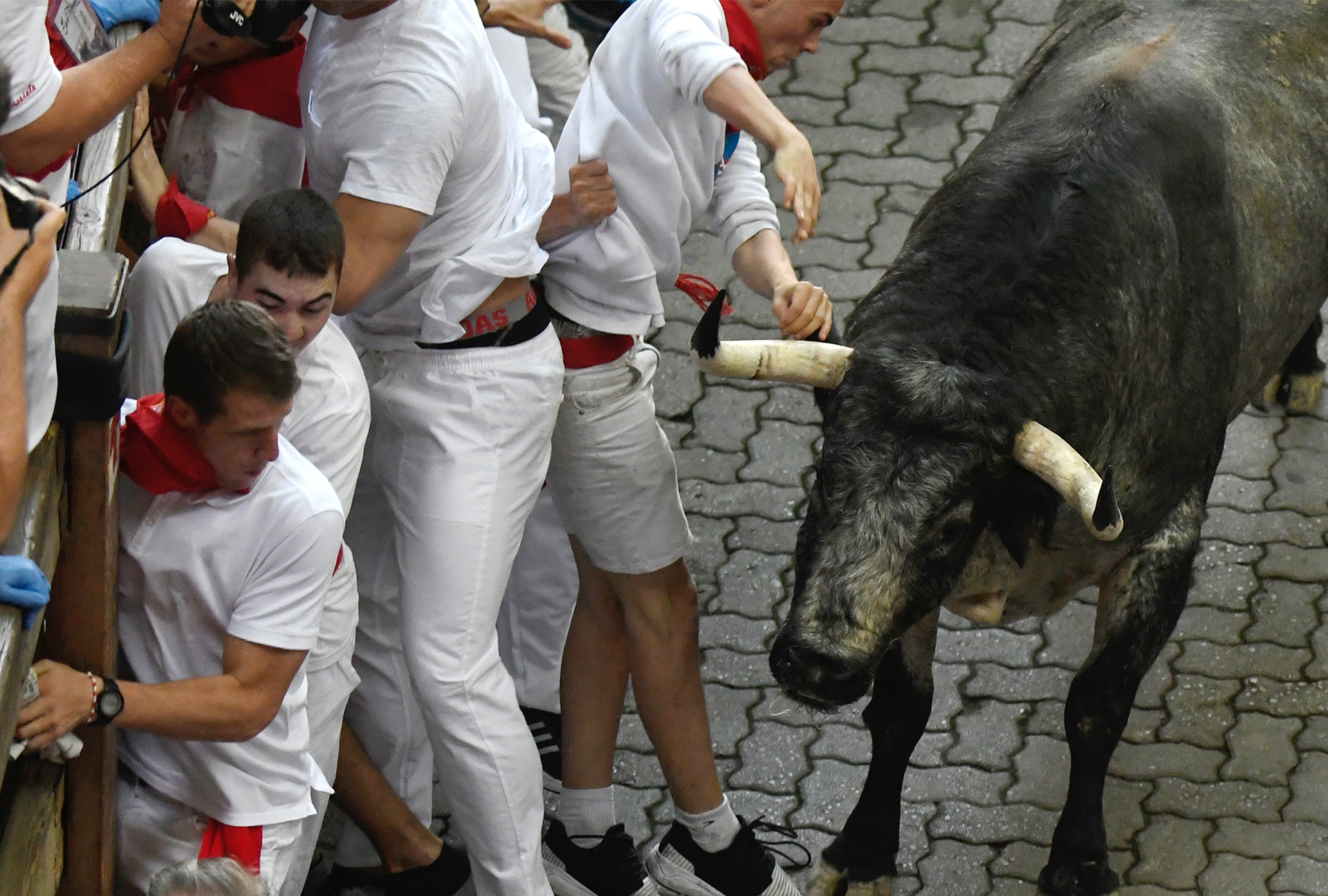 Cebada Gago's fighting bull runs past some participants on the first day of the San Fermin bull run festival in Pamplona, northern Spain on July 7, 2017. Each day at 8:00 am hundreds of people race with six bulls, charging along a winding, 848.6-metre (more than half a mile) course through narrow streets to the city's bull ring, where the animals are killed in a bullfight or corrida, during this festival, immortalised in Ernest Hemingway's 1926 novel "The Sun Also Rises" and dating back to medieval times and also featuring religious processions, folk dancing, concerts and round-the-clock drinking. / AFP PHOTO / MIGUEL RIOPA / 