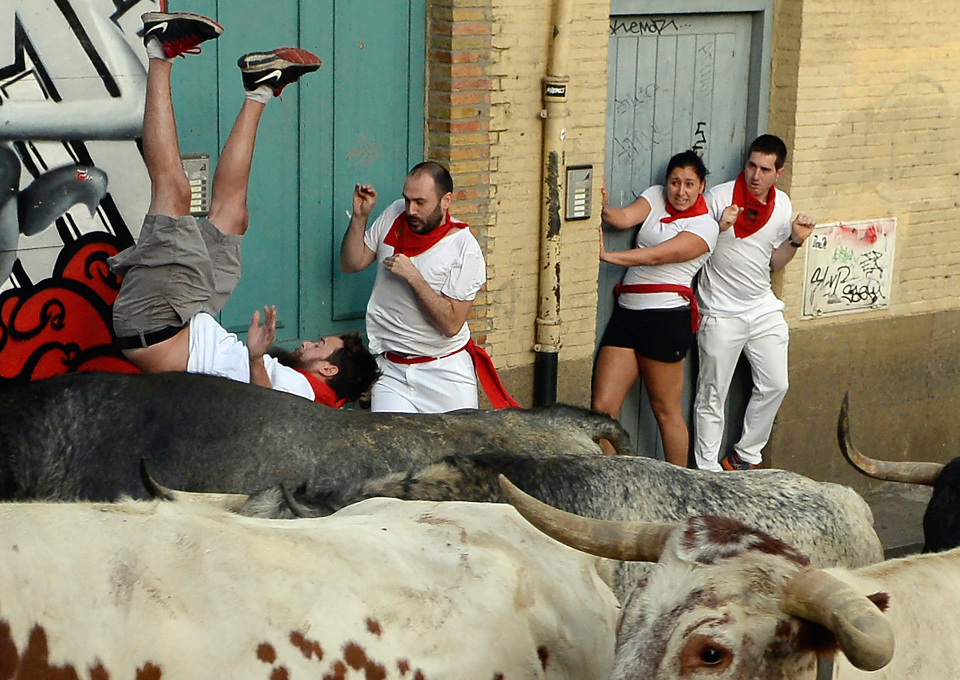A participant (L) is tossed by a Cebada Gago fighting bull on the first day of the San Fermin bull run festival in Pamplona, northern Spain on July 7, 2017. Each day at 8:00 am hundreds of people race with six bulls, charging along a winding, 848.6-metre (more than half a mile) course through narrow streets to the city's bull ring, where the animals are killed in a bullfight or corrida, during this festival, immortalised in Ernest Hemingway's 1926 novel "The Sun Also Rises" and dating back to medieval times and also featuring religious processions, folk dancing, concerts and round-the-clock drinking. / AFP PHOTO / ANDER GILLENEA / 